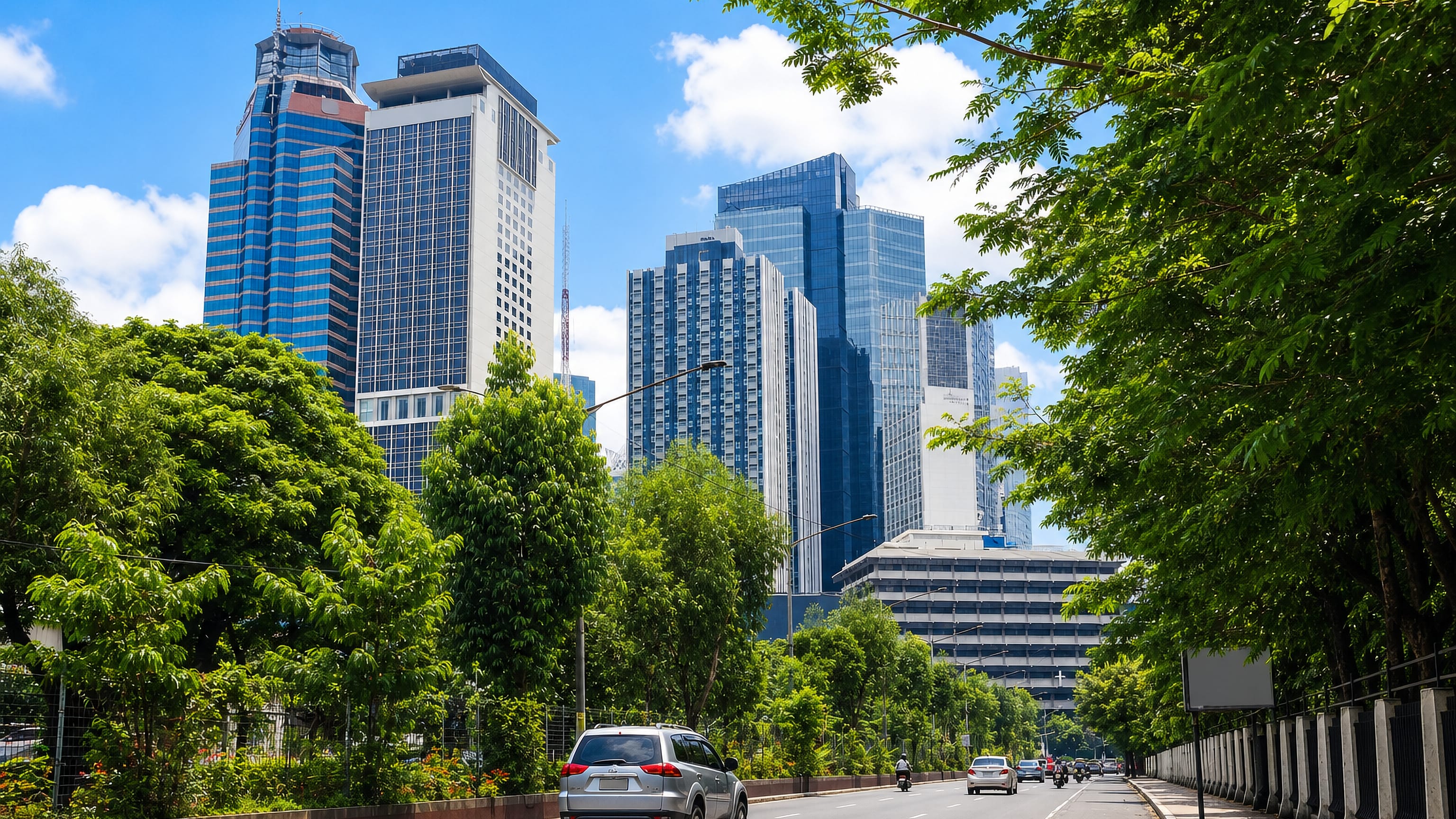 Tree-lined avenue in Pasig City leading toward the glass high-rises of the Ortigas Center business district.