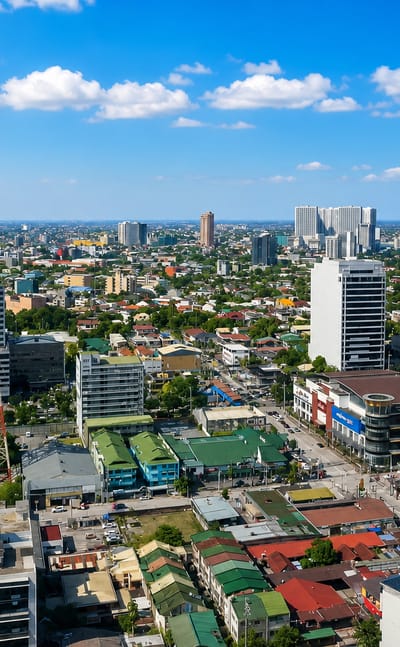 Aerial view of Quezon City's sprawl and mid-rise towers beside a tall red-and-white broadcast tower