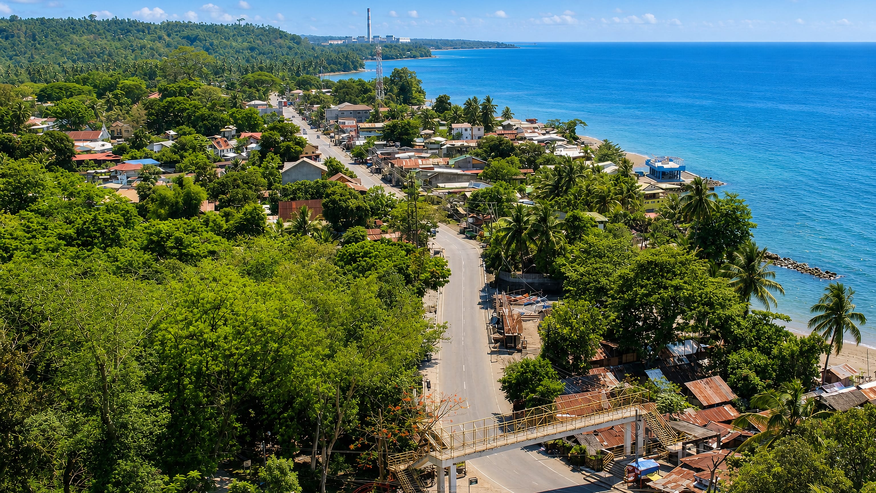 Coastal road and tin-roofed homes of Iligan curving along the palm-lined shore of Iligan Bay.
