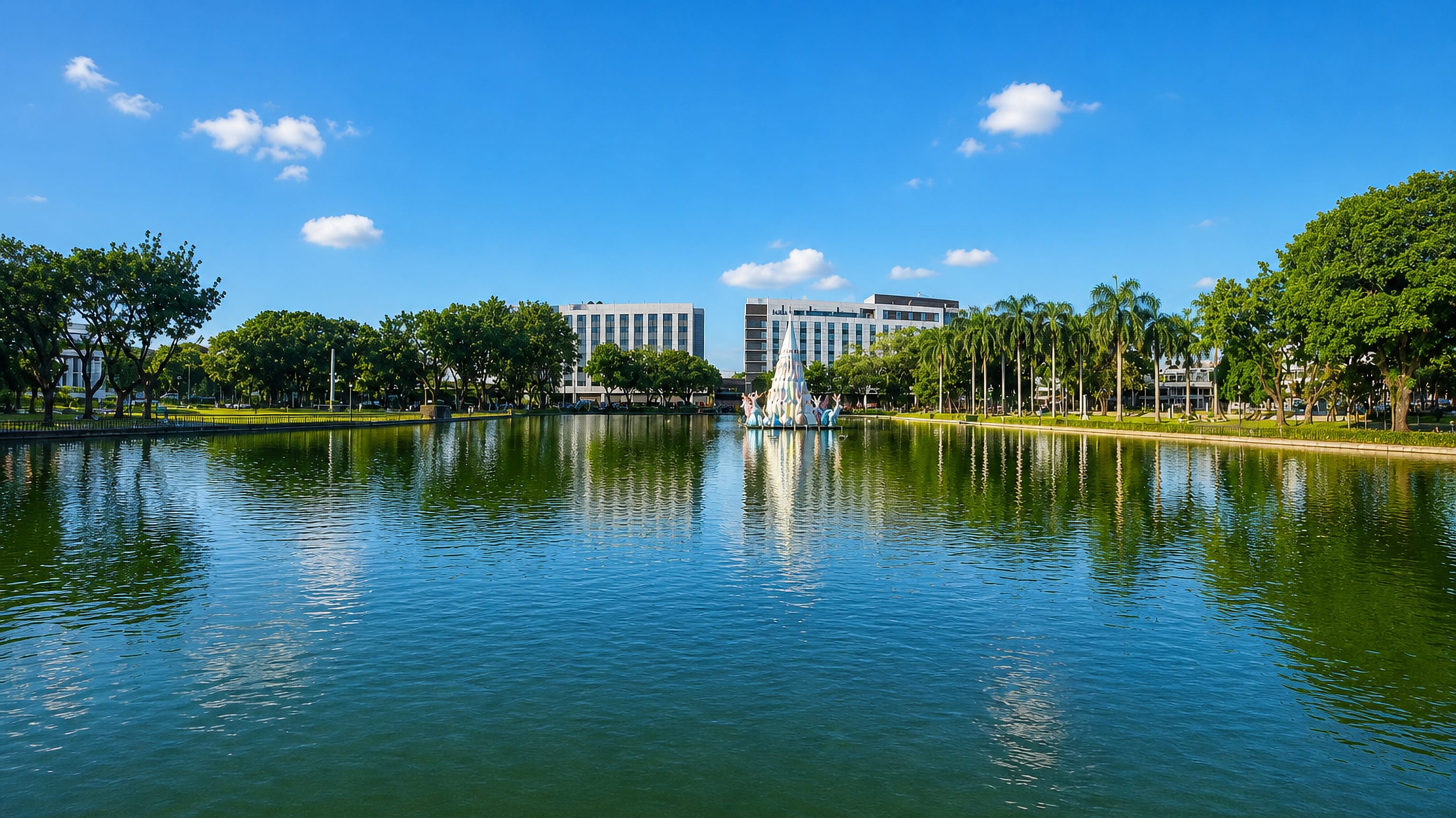 Bacolod City's lagoon in the Philippines, with a white fountain sculpture and civic buildings behind palms.