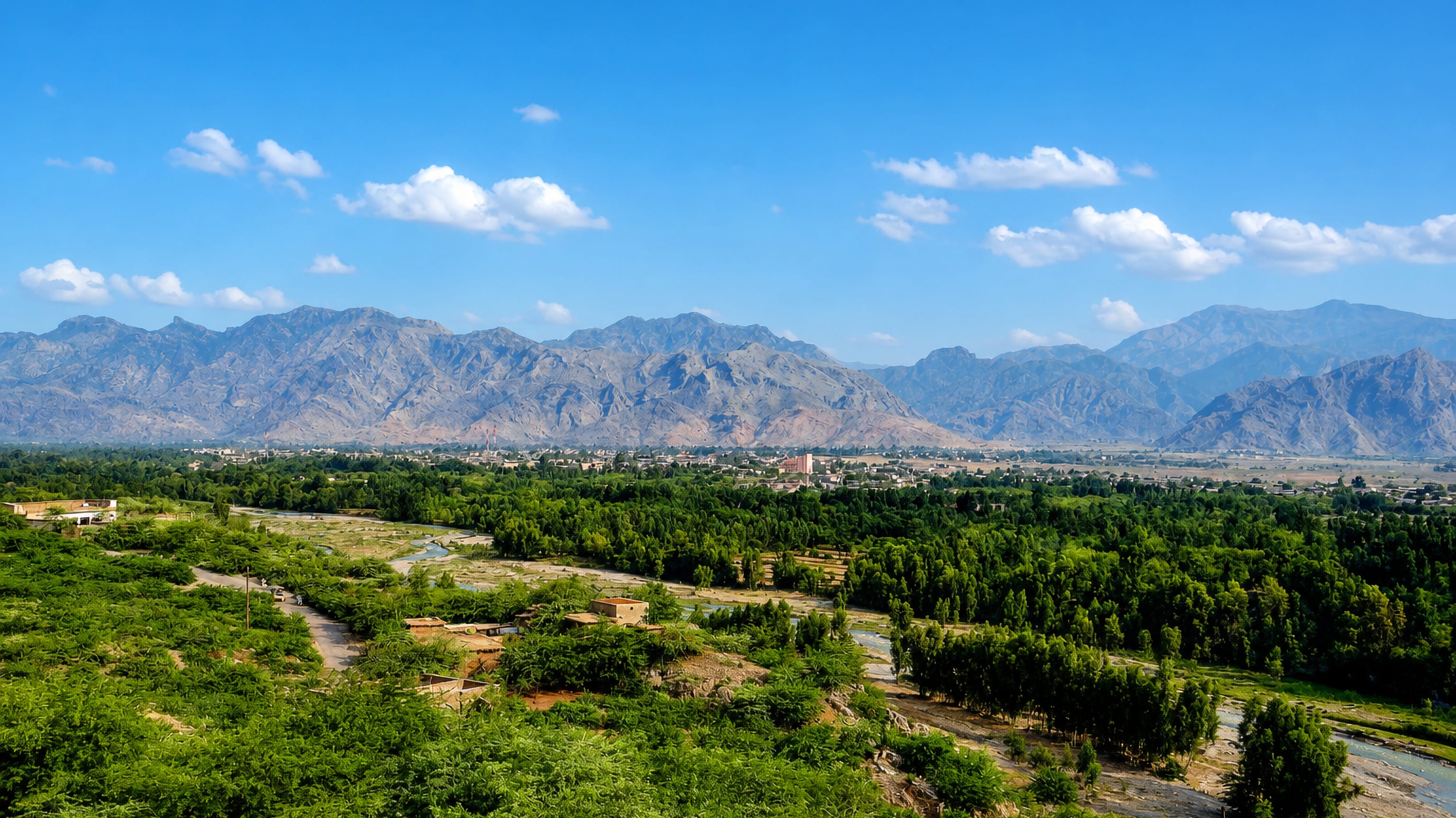 Green valley farmland and scattered houses at Kohat, Pakistan, below the surrounding rocky hills