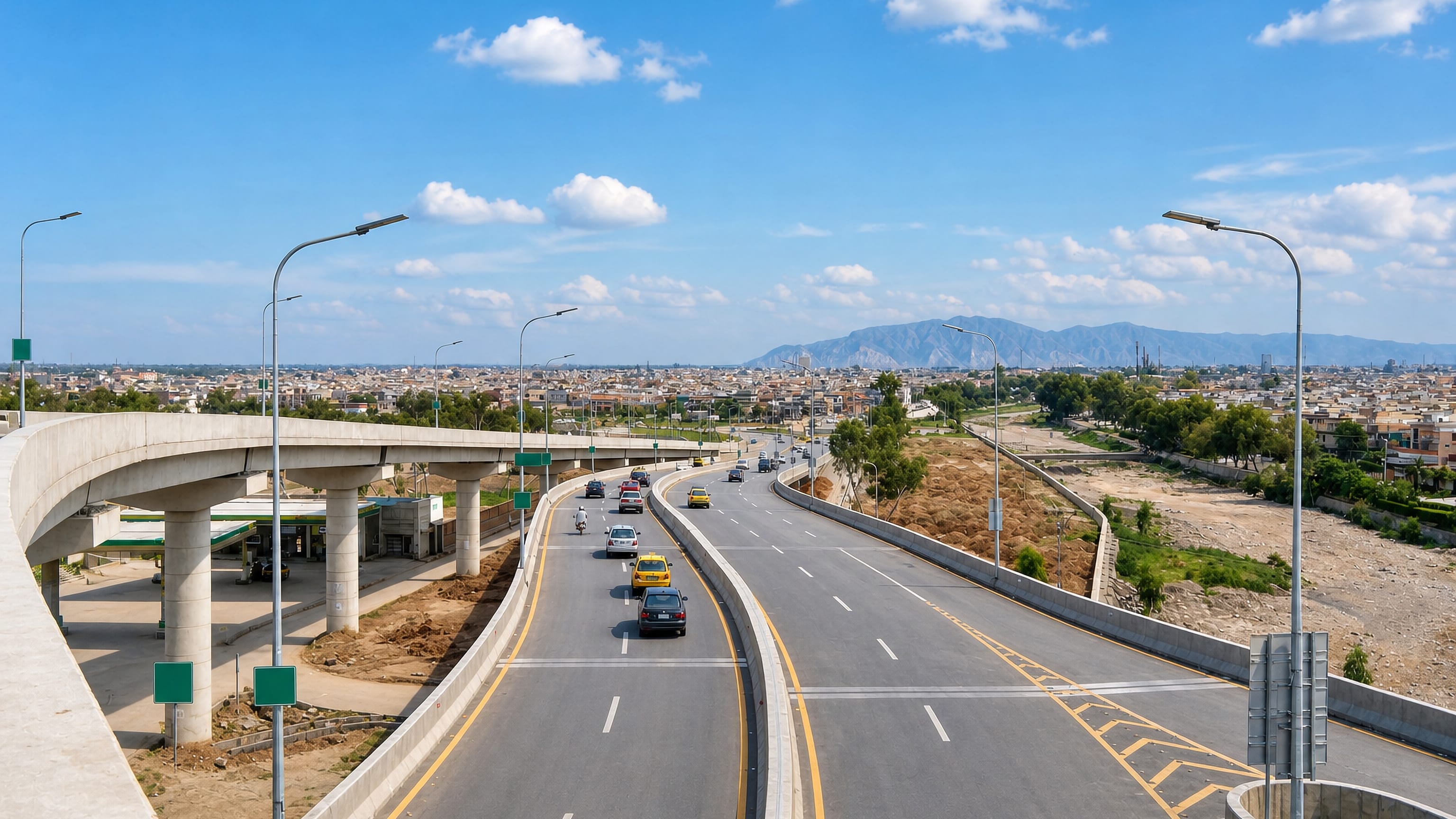 Sunlit multi-lane flyover and ring road curving past Hayatabad's rooftops in Peshawar, with hills beyond