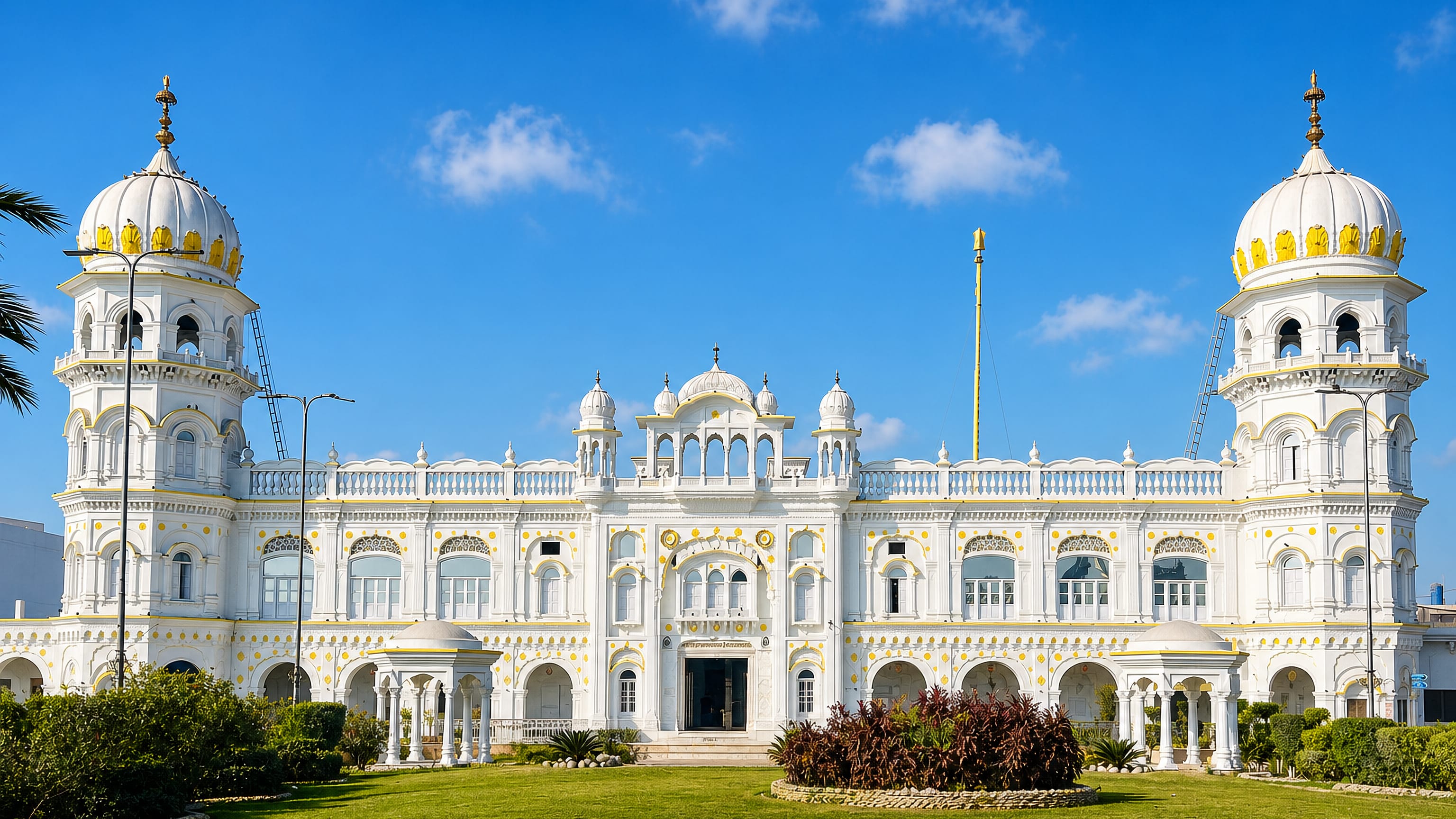 The white and gold domes of Gurdwara Janam Asthan in Nankana Sahib, Pakistan, above its lawns.