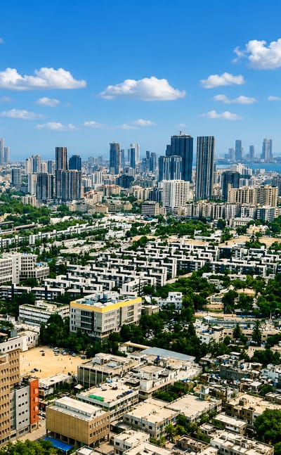 Aerial view of Karachi with a dense high-rise skyline rising behind low residential blocks near the coastline.