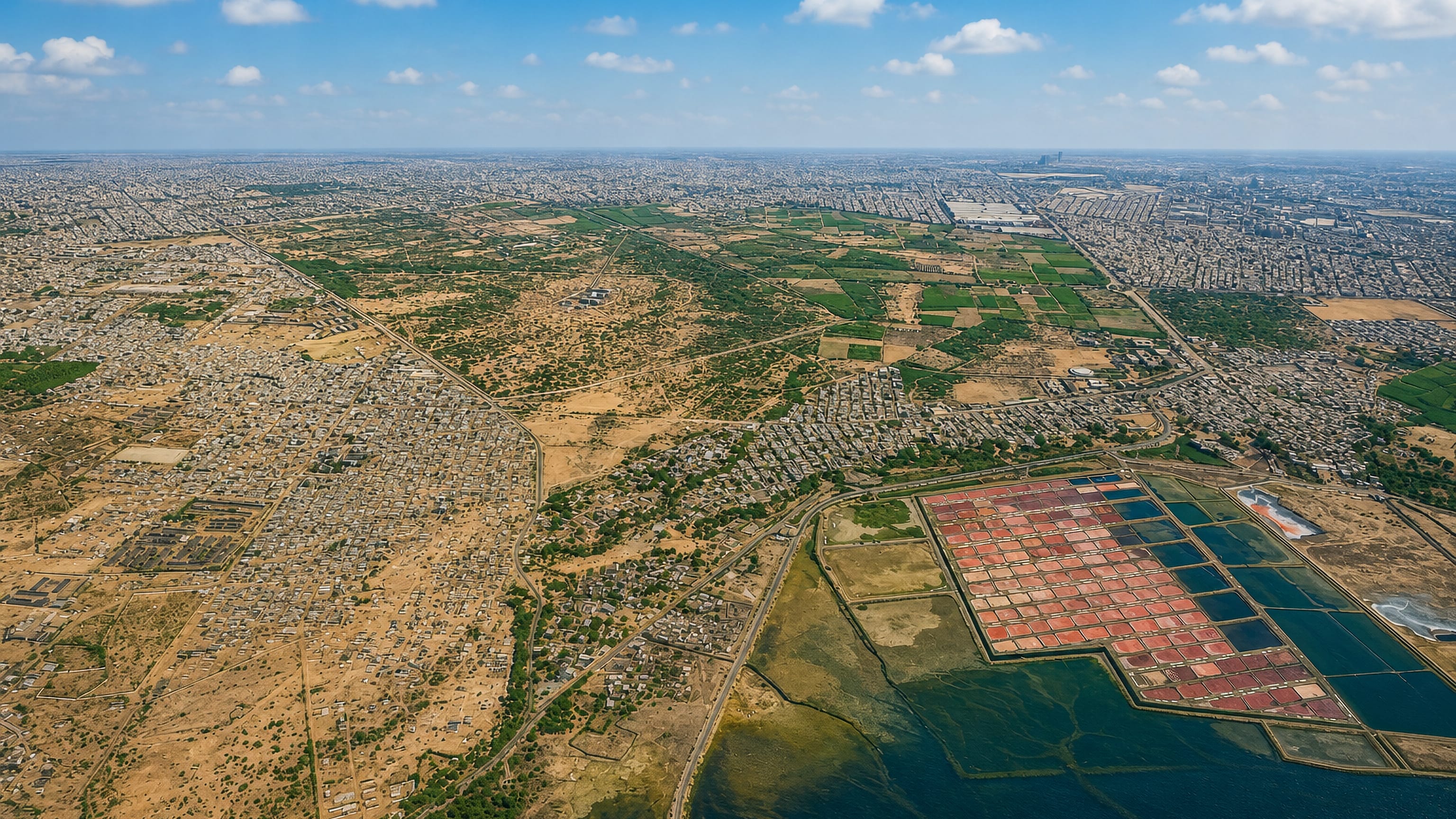 Aerial over the dense sprawl of Landhi in eastern Karachi, with salt pans and creek water to the south
