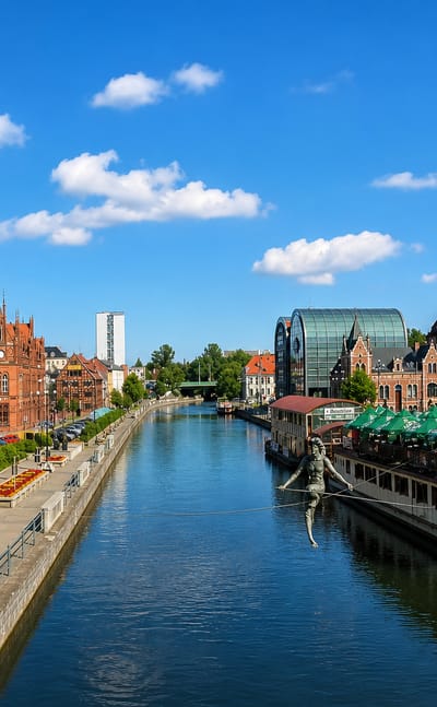 Bydgoszcz's Brda River waterfront with half-timbered granaries, historic townhouses and the tightrope-walker sculpture.