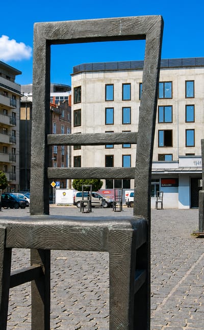 Bronze empty-chair memorial sculptures on the cobbled Plac Bohaterow Getta square in Krakow's former Jewish ghetto.