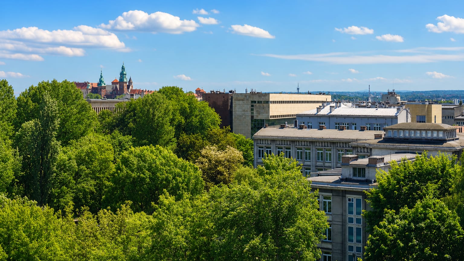 Rooftops and greenery of Krowodrza with the spires of Wawel Castle rising on the Krakow skyline behind