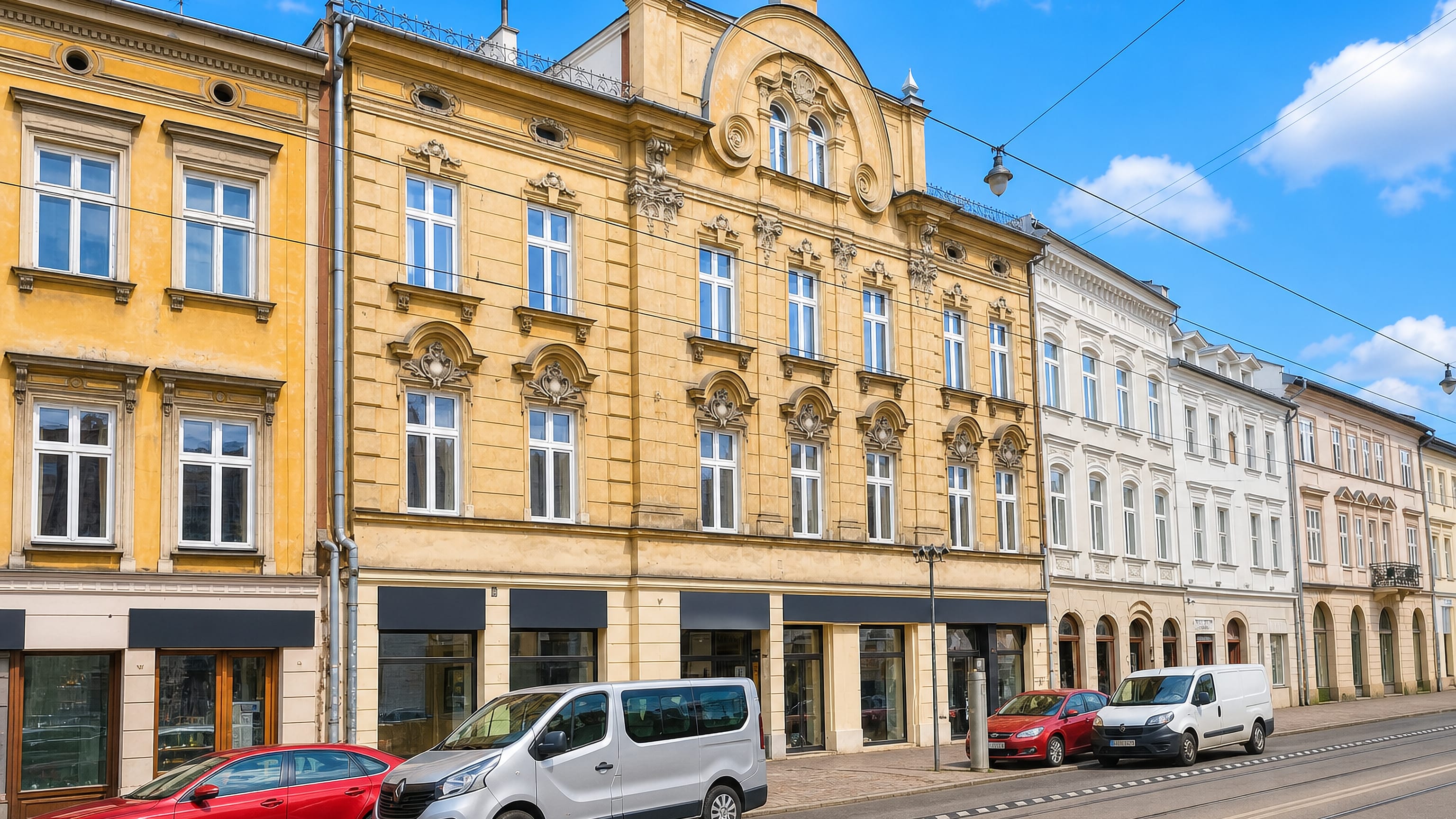 Ornate 19th-century tenements above shopfronts along a tram street in Krakow's Stradom district