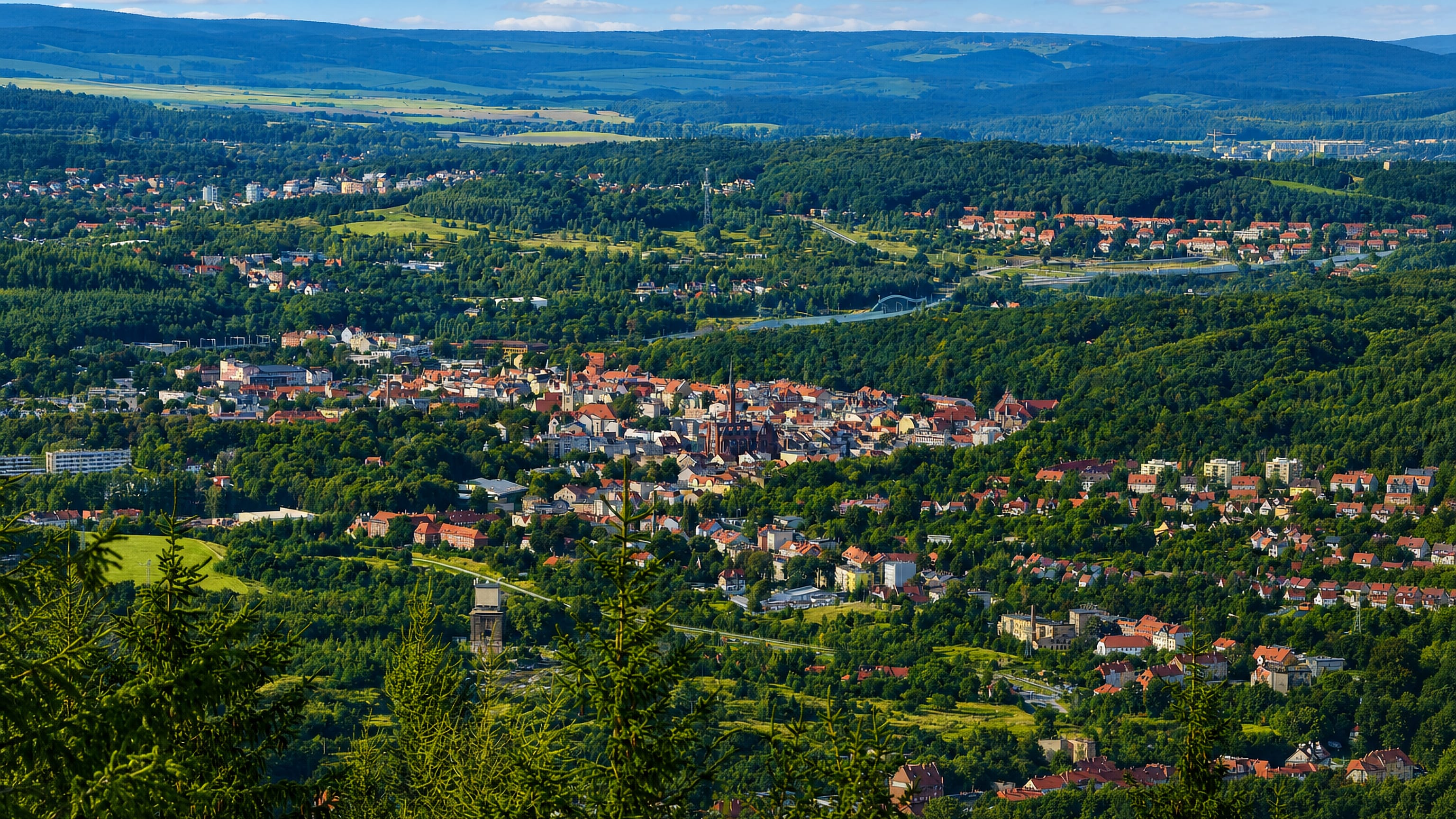 Hilltop panorama of Walbrzych, Poland, its church spire and red roofs set in a forested Sudeten valley.