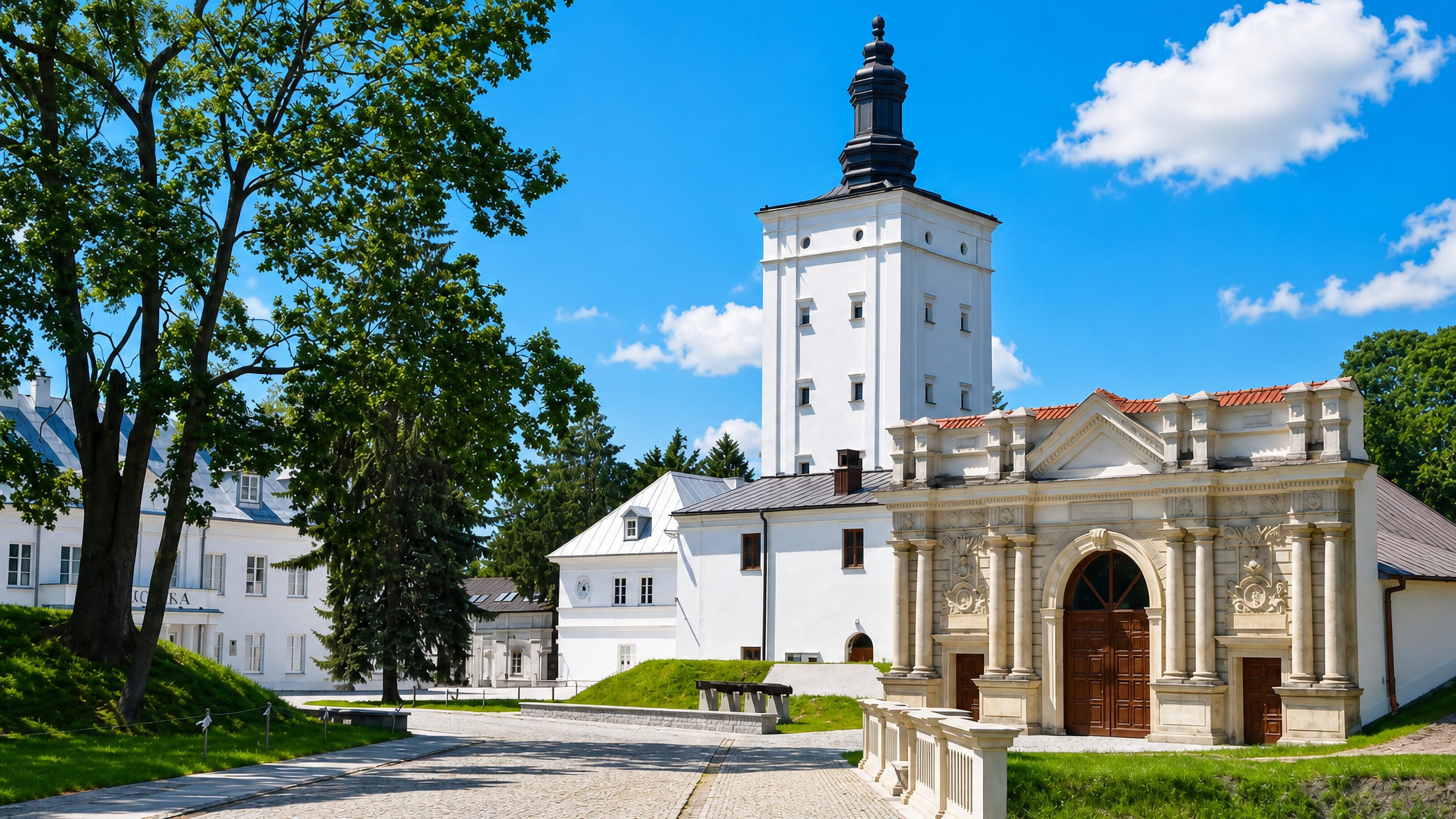 White gate tower and baroque chapel of the Radziwiłł castle park in Biała Podlaska, Poland, on a sunny day.