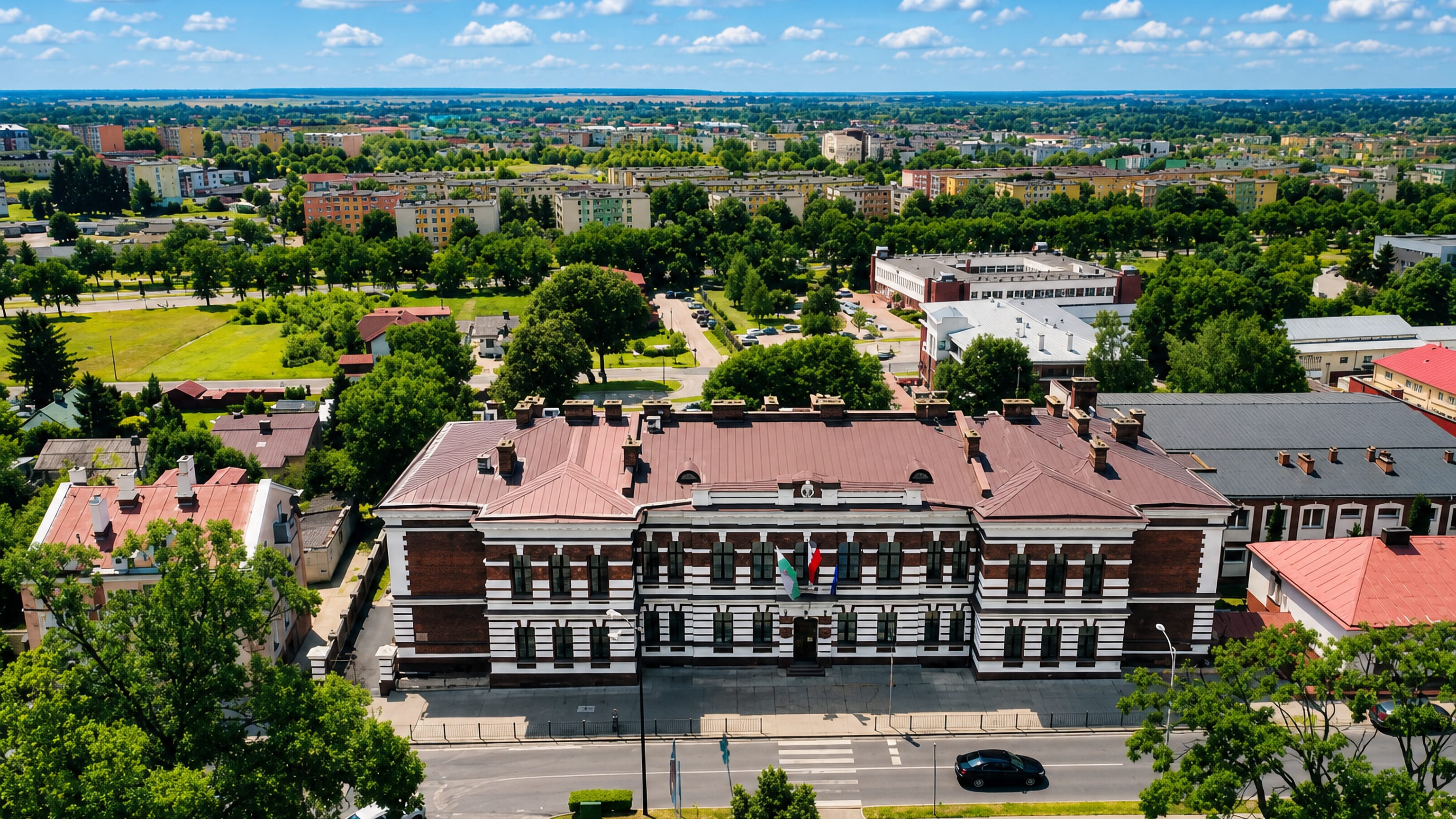 Aerial view over Chełm, Poland, with a brick-and-white civic building among low-rise housing and greenery