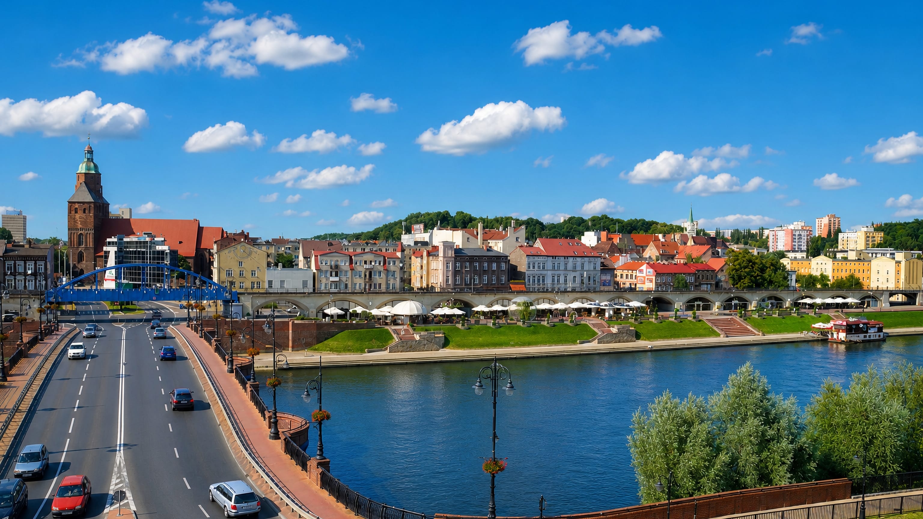 Gorzów Wielkopolski's Warta riverfront, blue arch bridge and cathedral tower with its green copper dome.
