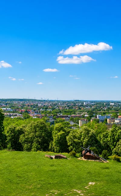 Green hilltop overlooking the townscape of the Chelm district of Gdansk with a domed building beyond.