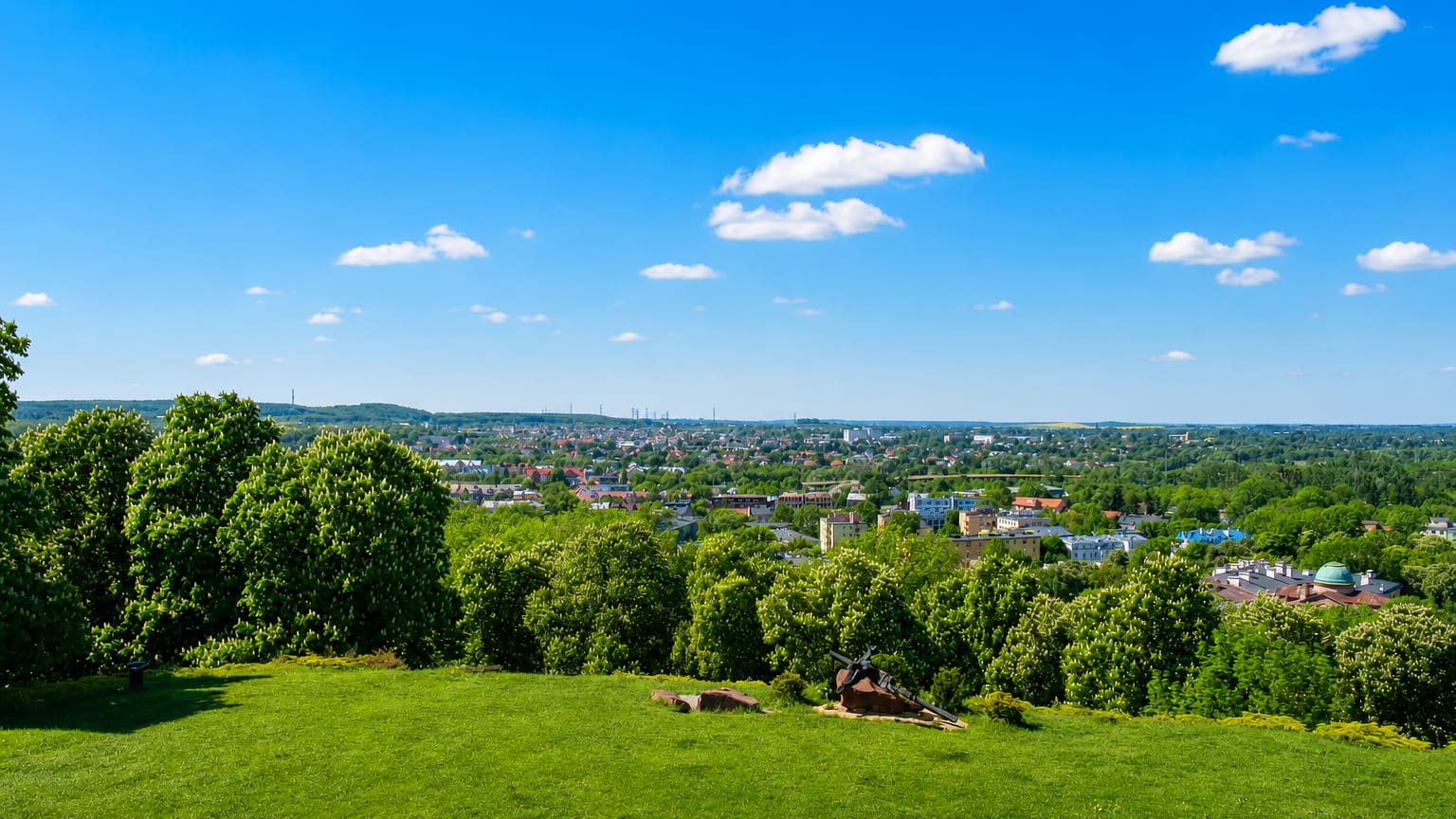 Green hilltop overlooking the townscape of the Chelm district of Gdansk with a domed building beyond.