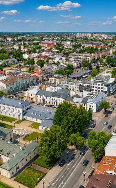 Aerial over the Siedlce district of Gdańsk with a green-domed historic building, mid-rise streets and greenery.