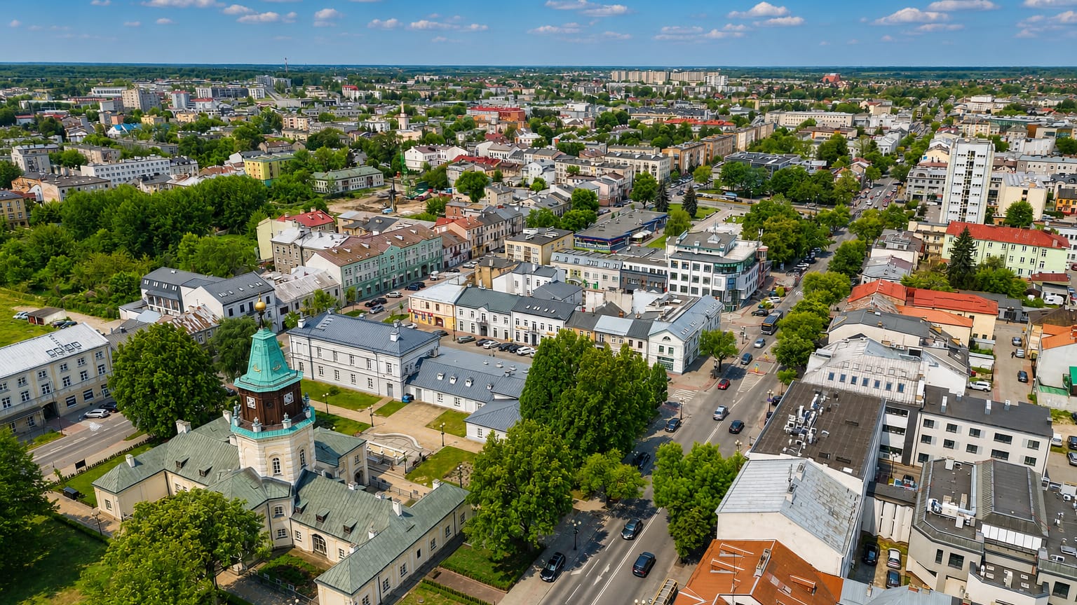 Aerial over the Siedlce district of Gdańsk with a green-domed historic building, mid-rise streets and greenery.