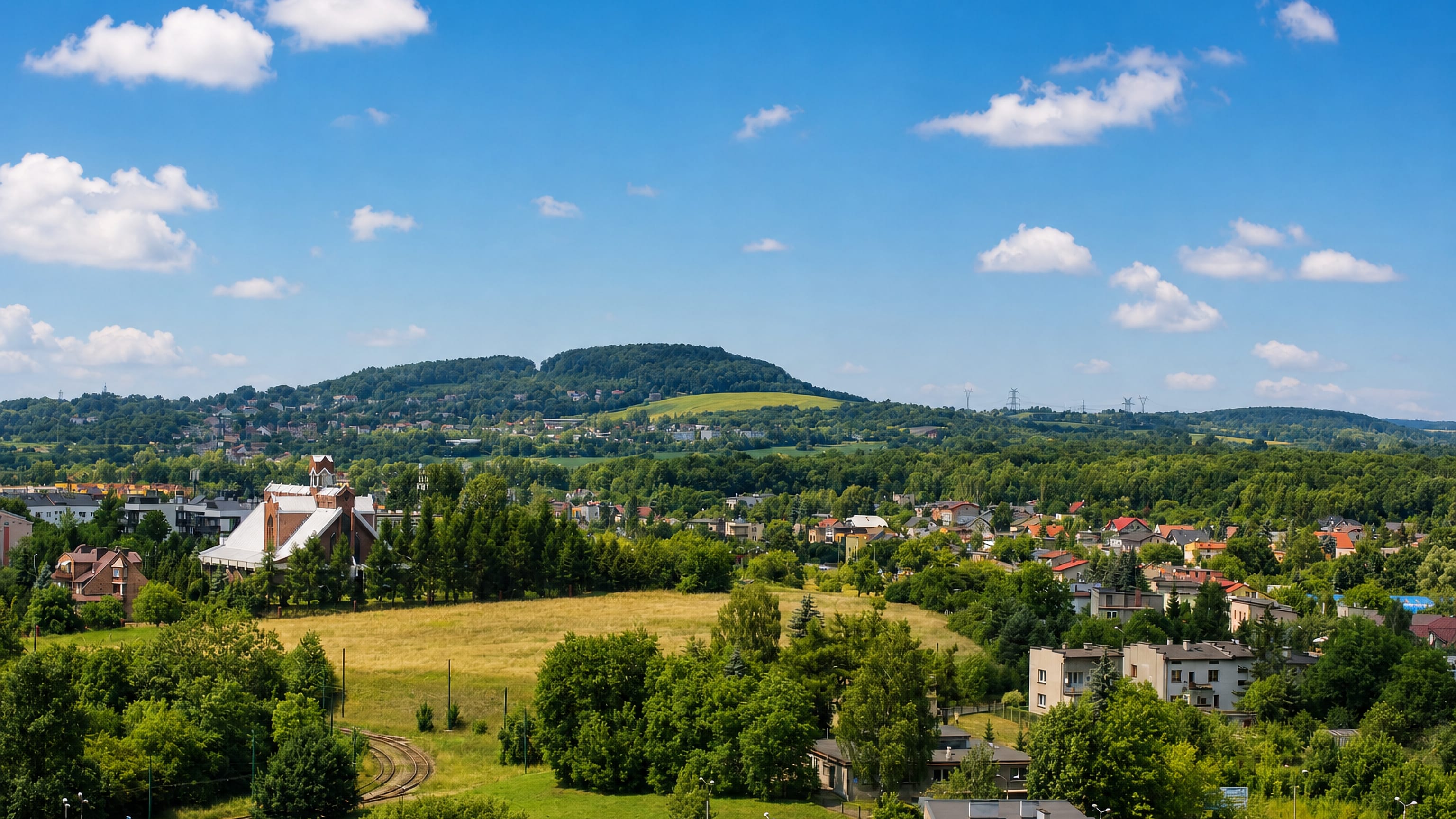 Grodziec in Bedzin spread below a wooded ridge, with its brick church, open meadows and curving tram tracks.