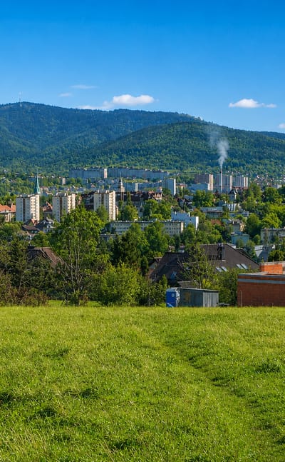 Bielsko-Biala, Poland, nestled below the forested Beskid mountains, seen across a green meadow