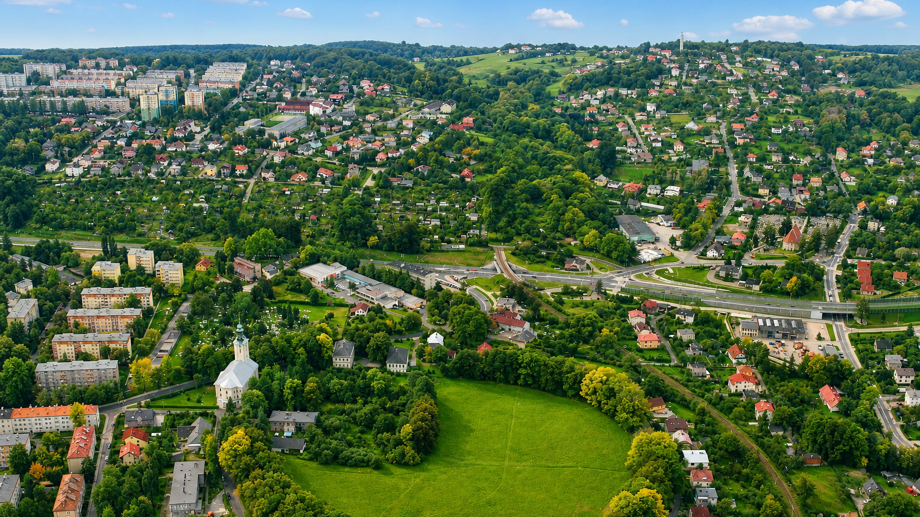Aerial over the white church, meadow and wooded hills of Stare Bielsko in Bielsko-Biała.