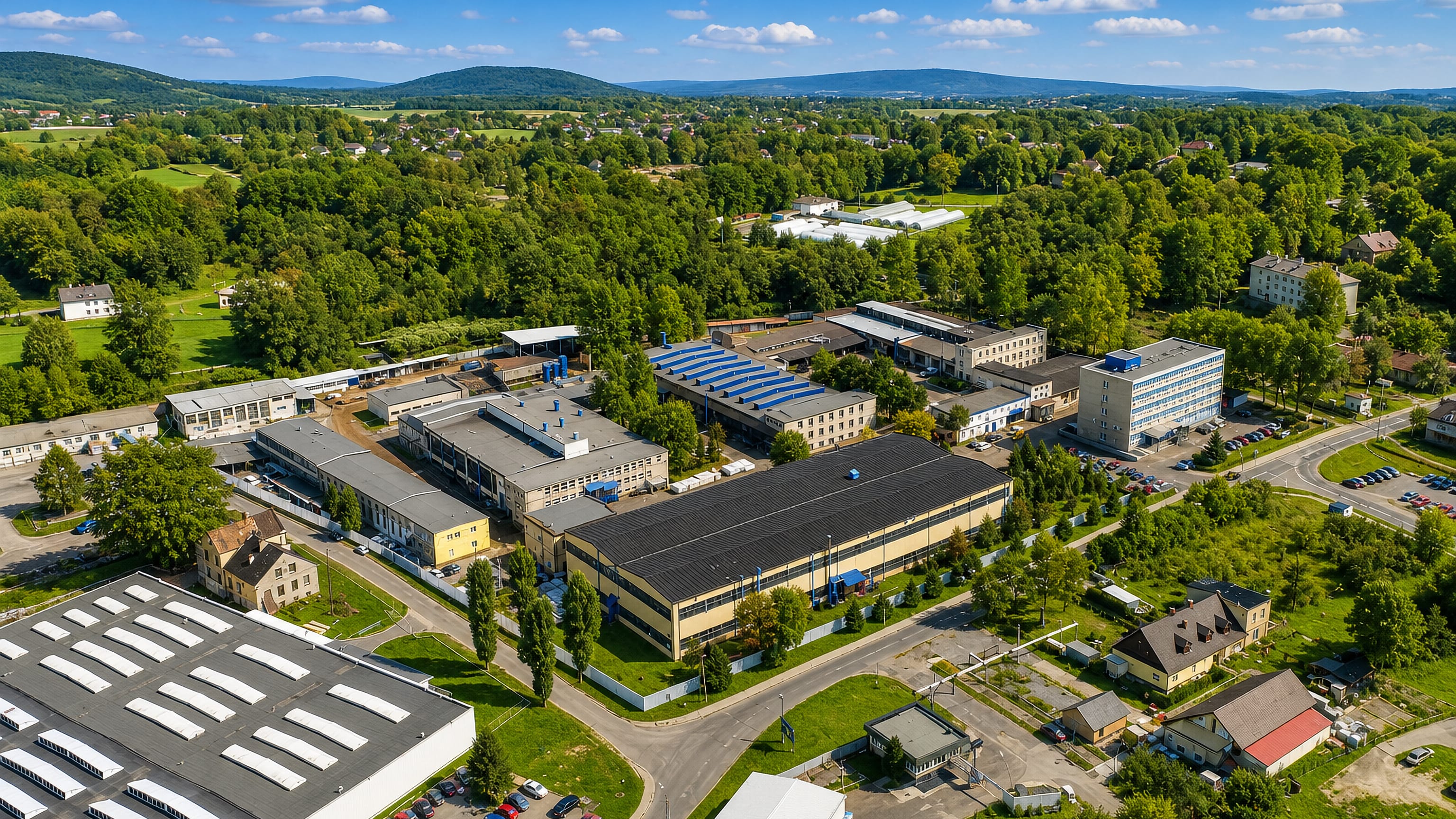 Aerial view of Wapienica's factory halls in Bielsko-Biała, ringed by woodland and Beskid hills.