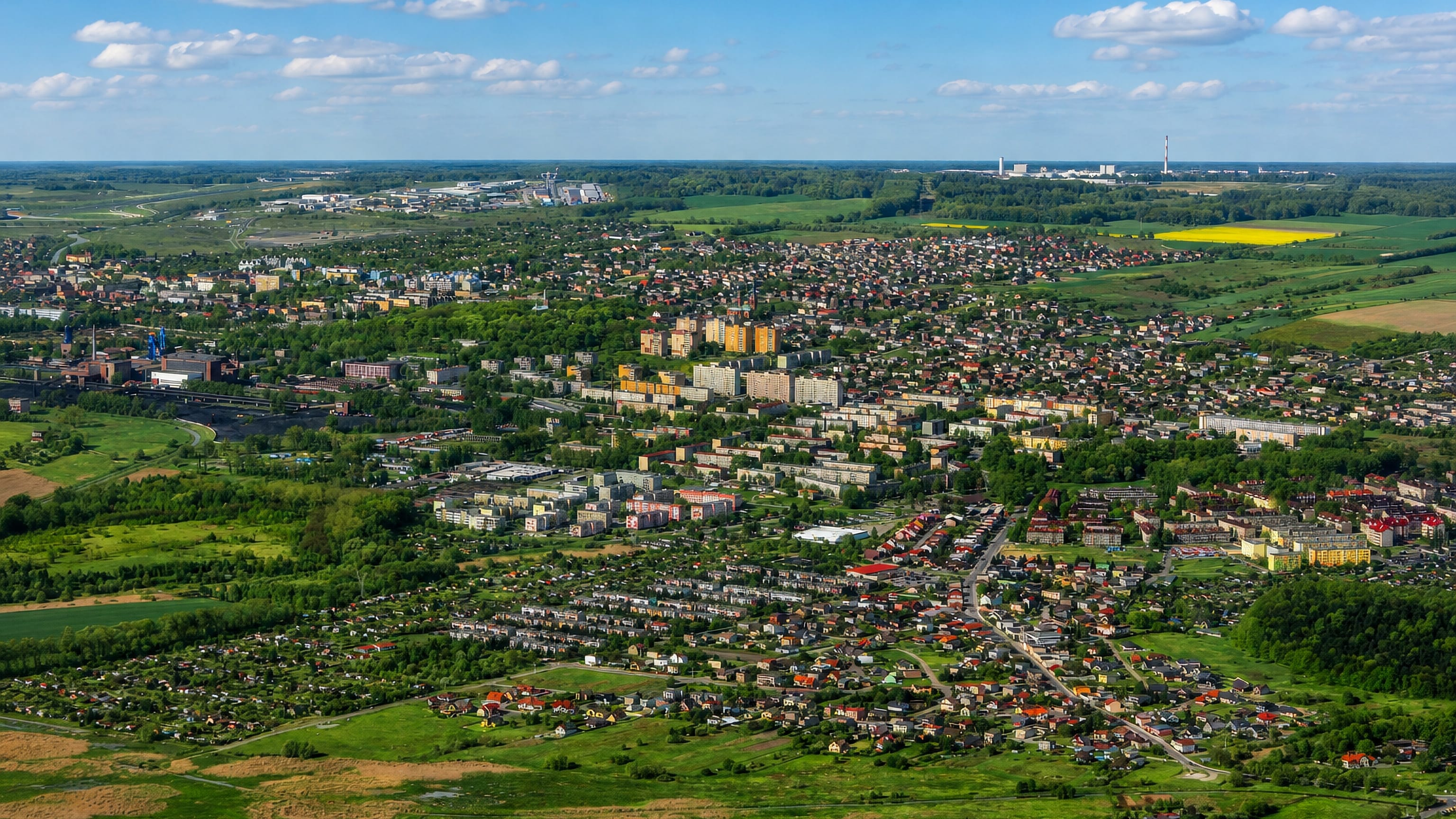 Aerial view of Piekary Śląskie, Poland, with houses, apartment blocks, mine buildings and green fields beyond