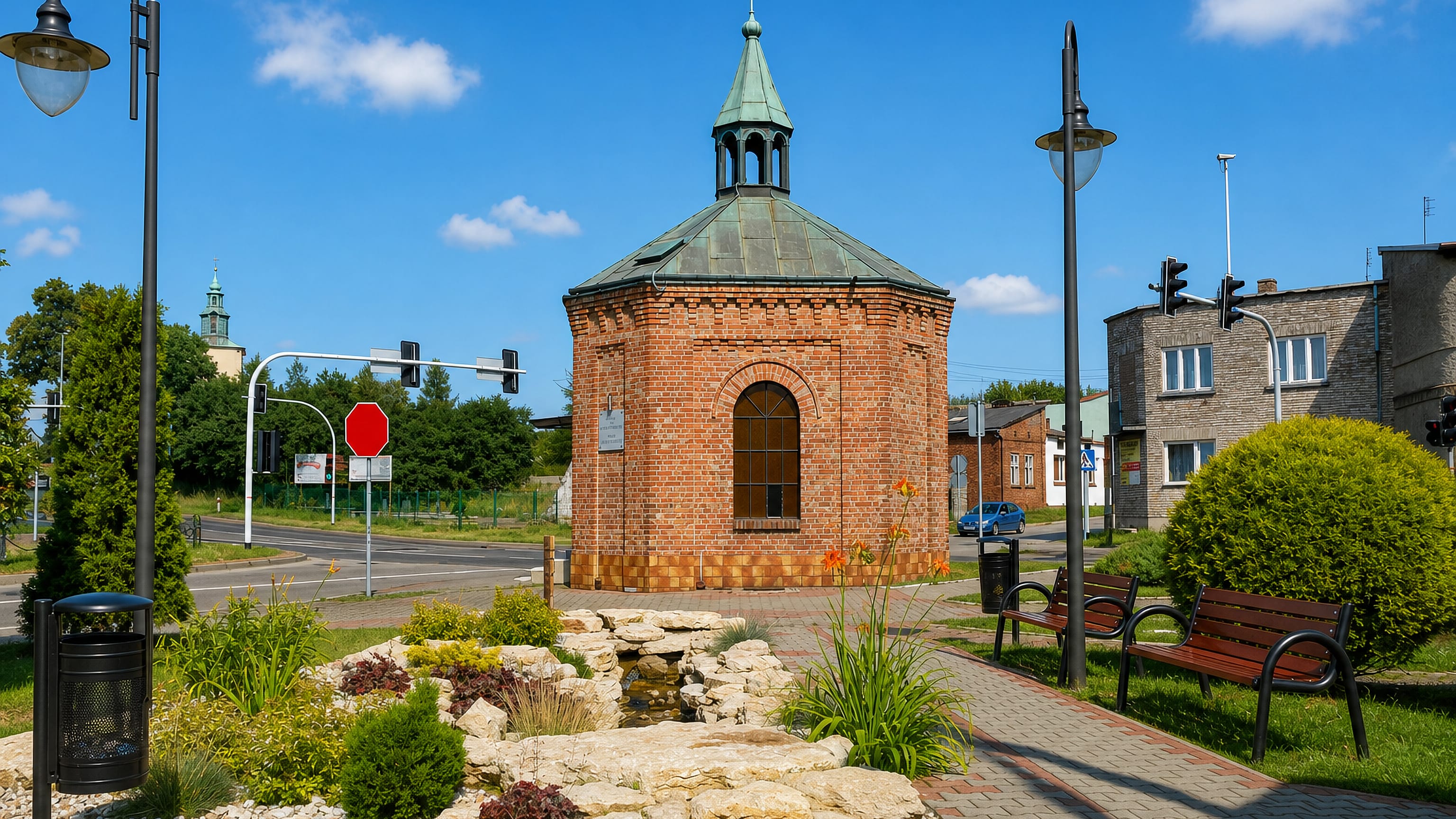 Brick chapel with a copper spire beside a landscaped rockery and spring in Kromołów, Zawiercie.