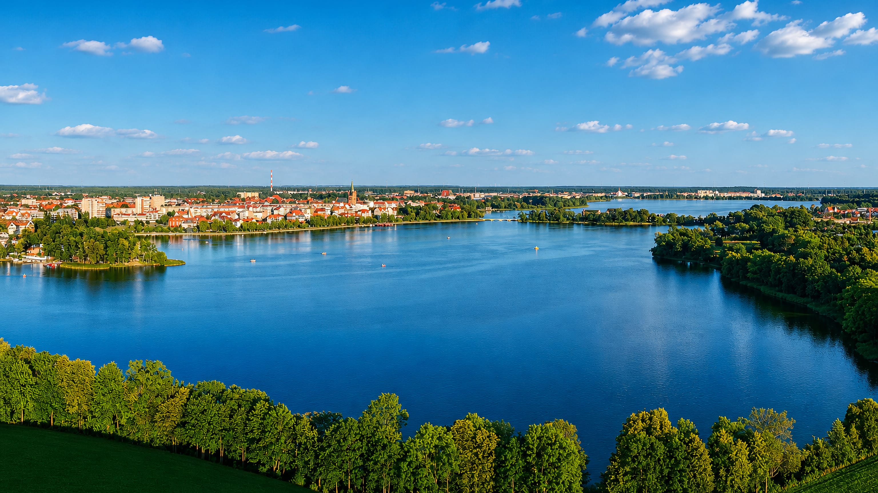 Lake Elckie curving past the town of Elk, Poland, with wooded shores and church spires on the far bank.