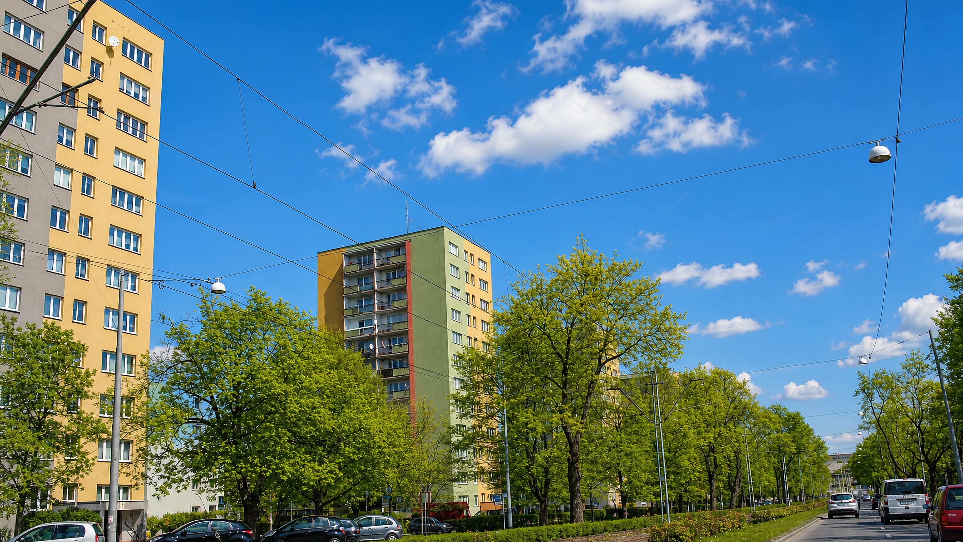 Tram line and tree-lined avenue beside colourful high-rise housing blocks in Świerczewo, Szczecin.