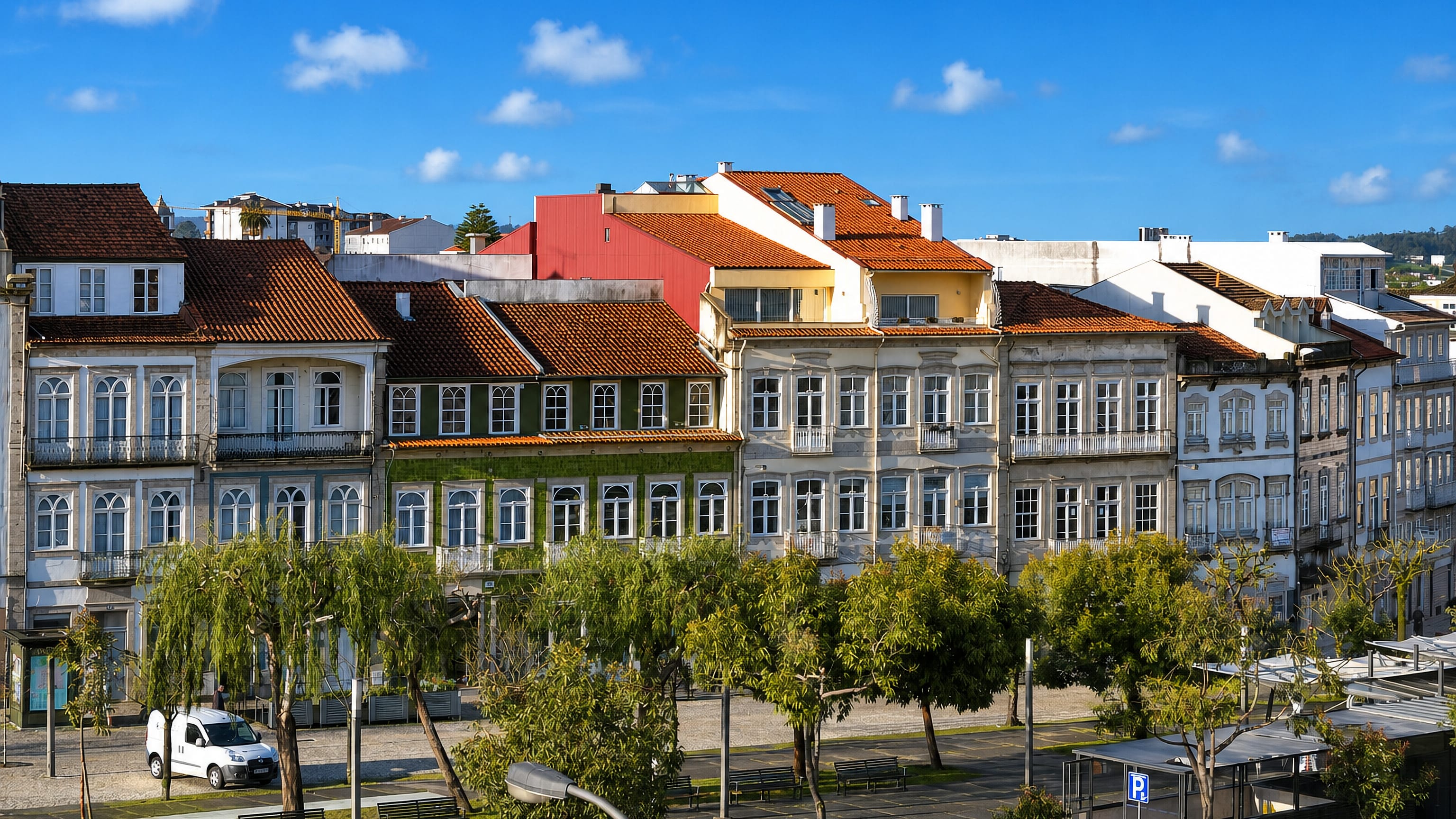 Row of tiled-roof townhouses above a tree-lined pedestrian square in central Braga.
