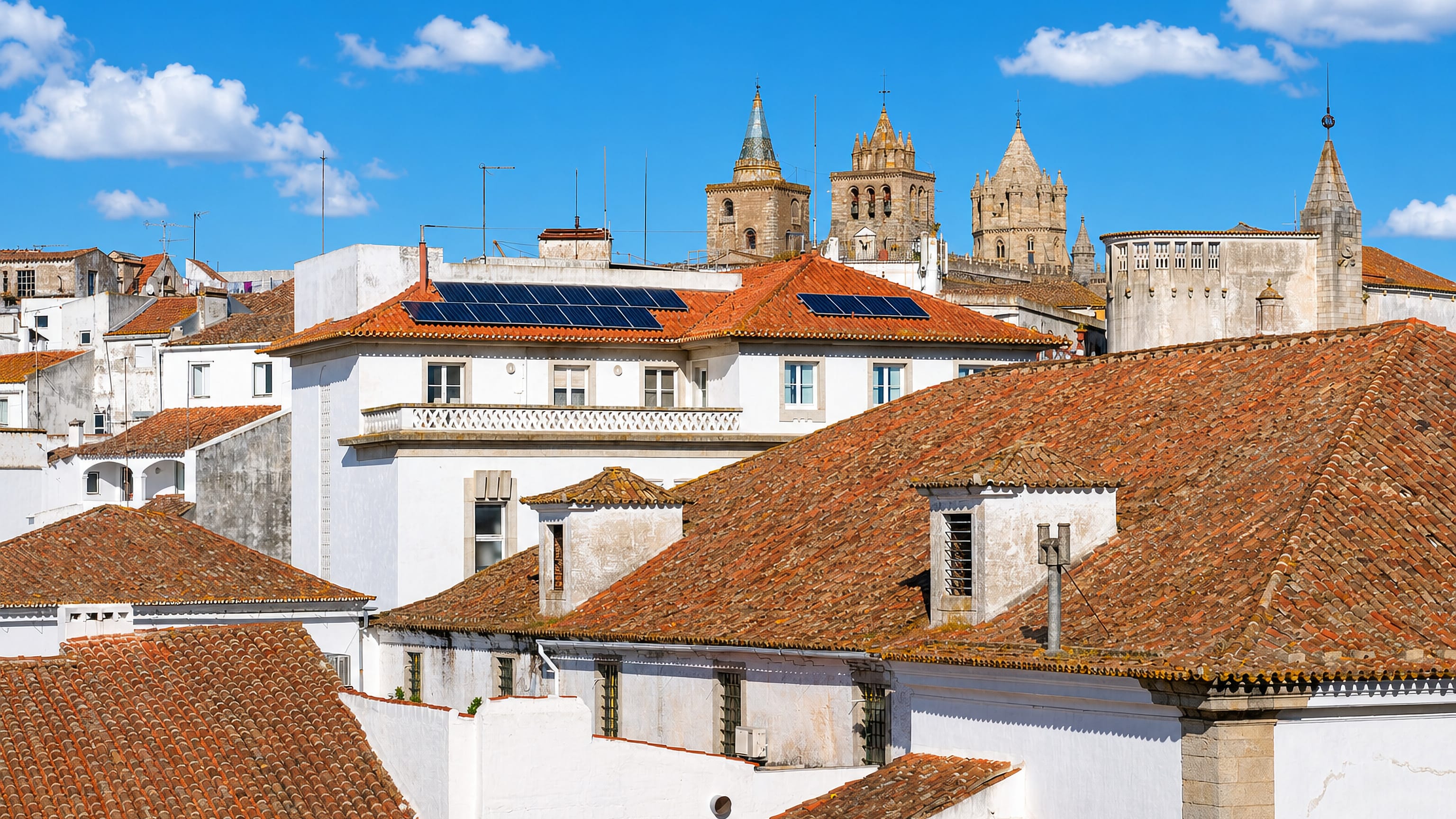 Whitewashed walls and terracotta rooftops of Évora with the towers and lantern of Évora Cathedral rising behind