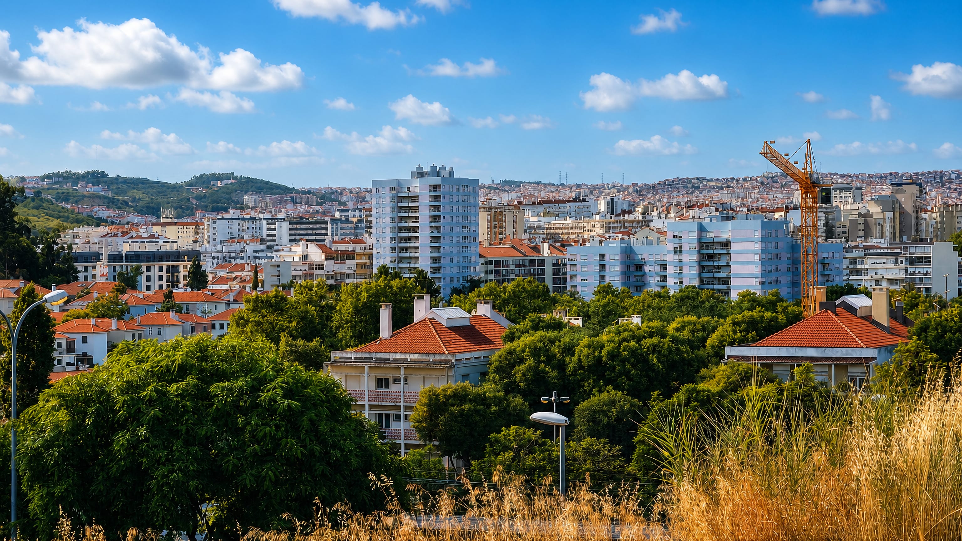 Hillside apartment blocks and tiled villas above trees in the Benfica district of Lisbon