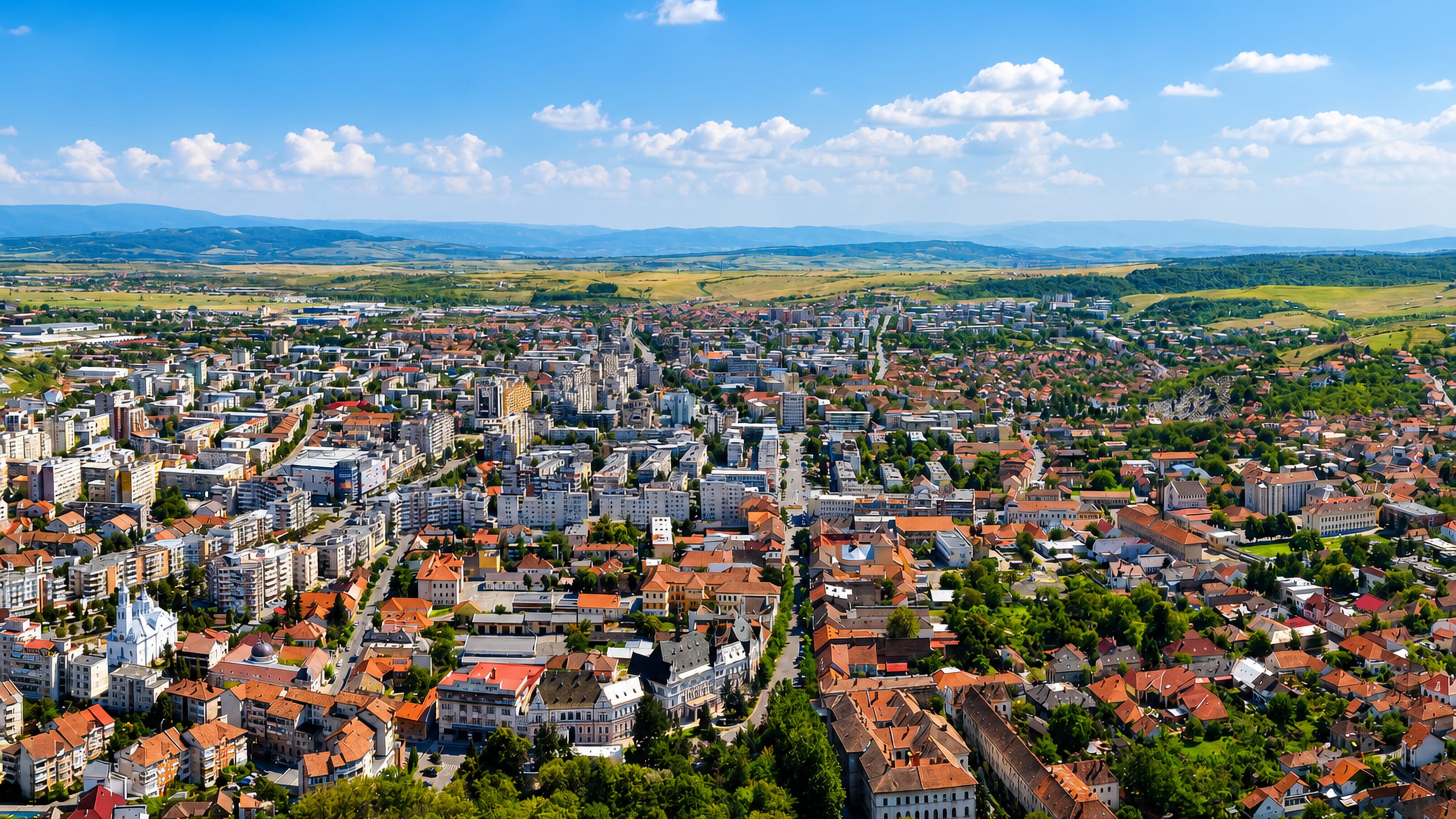 Deva, Romania seen from the citadel hill, red-roofed old town and apartment blocks below the Carpathian foothills.