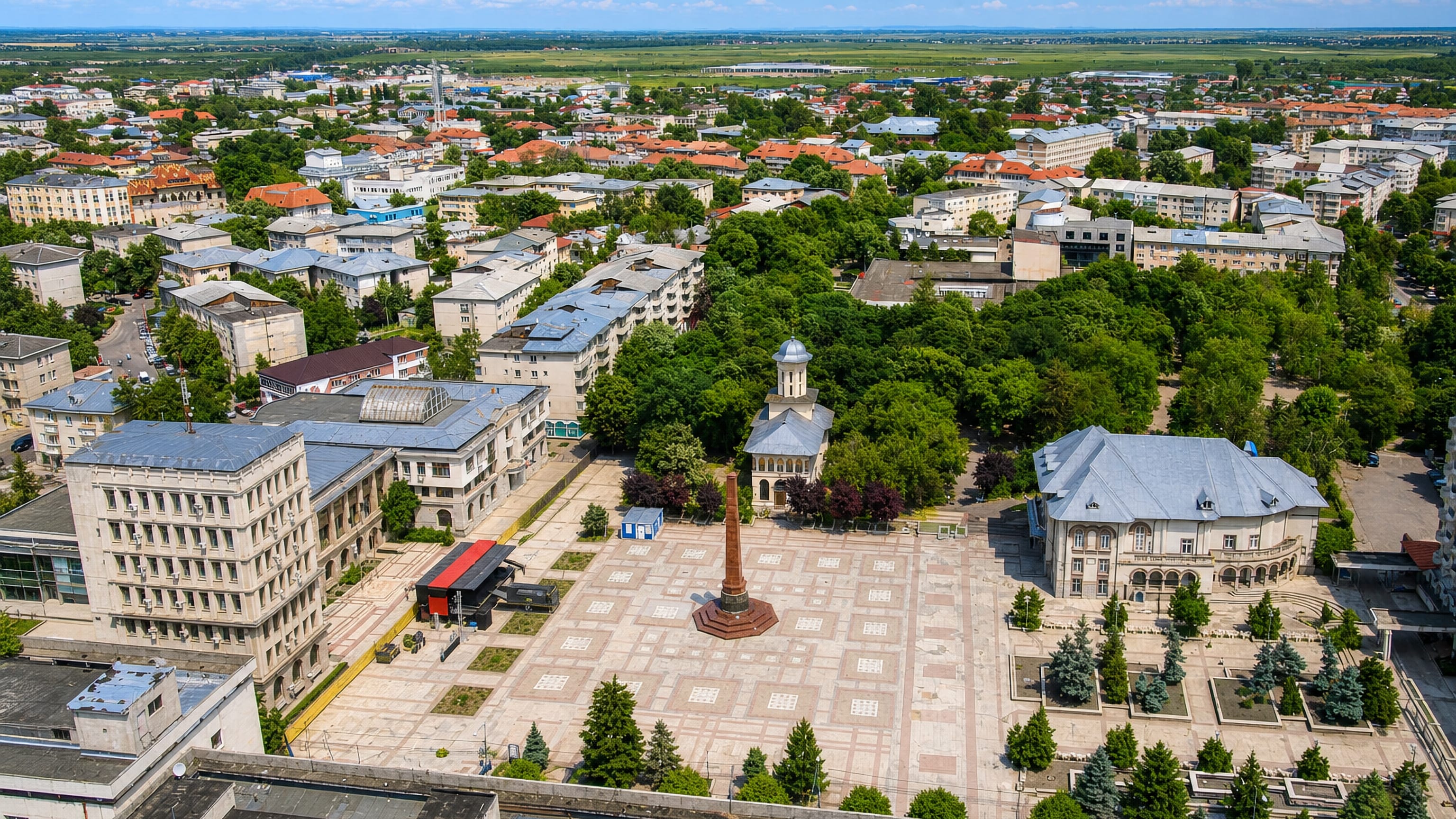 Aerial view of Focșani's central Union Square with its stone obelisk monument, church and low-rise Romanian townscape.