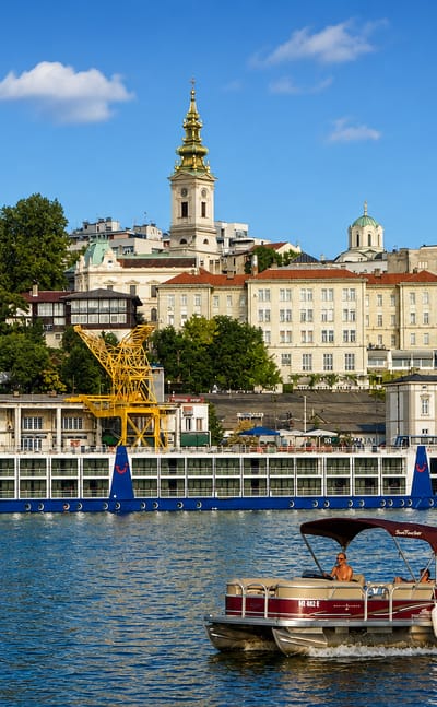 Belgrade's Stari Grad old town skyline with a cathedral spire rising above the Sava riverfront and moored boats.