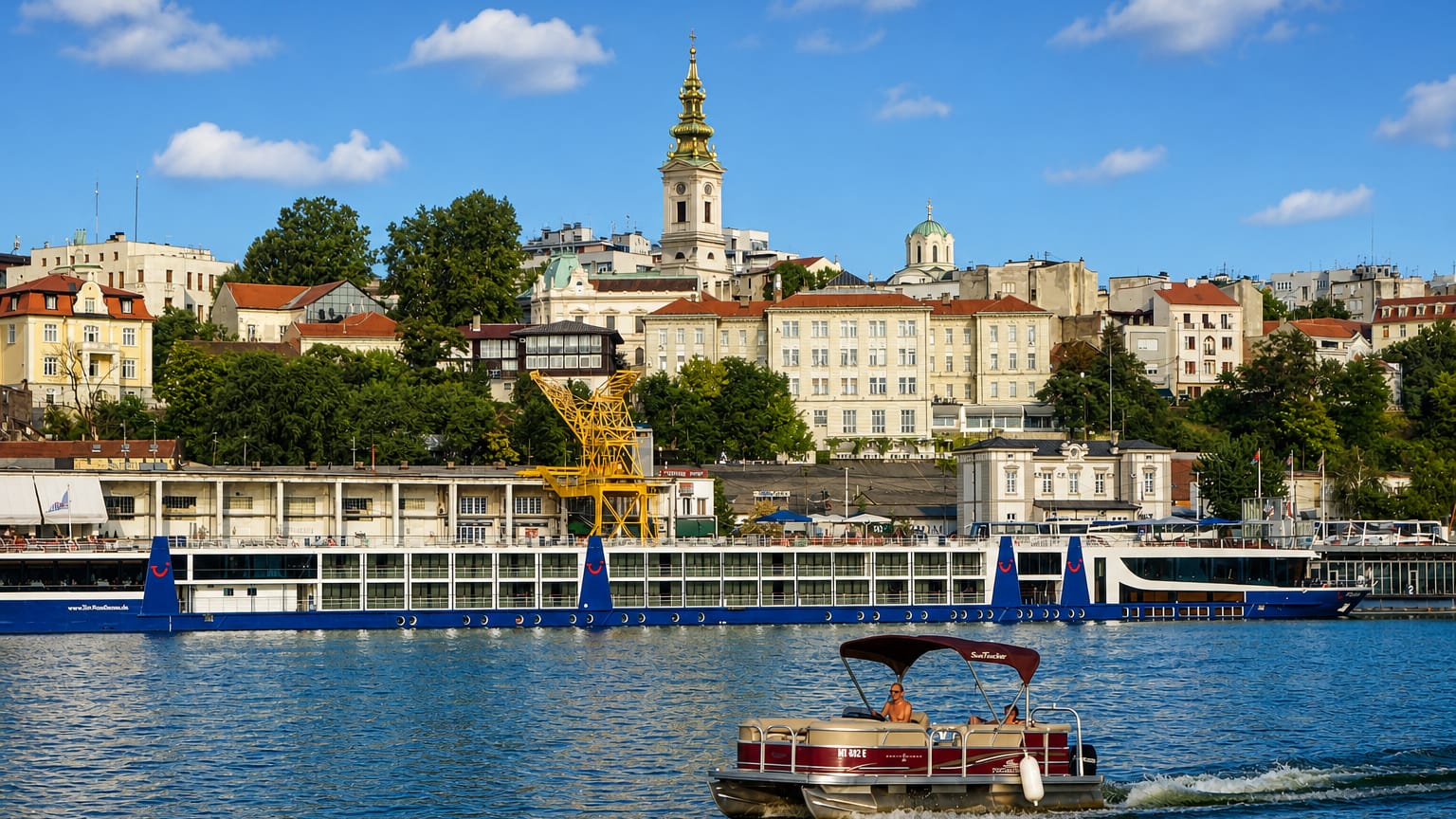 Belgrade's Stari Grad old town skyline with a cathedral spire rising above the Sava riverfront and moored boats.