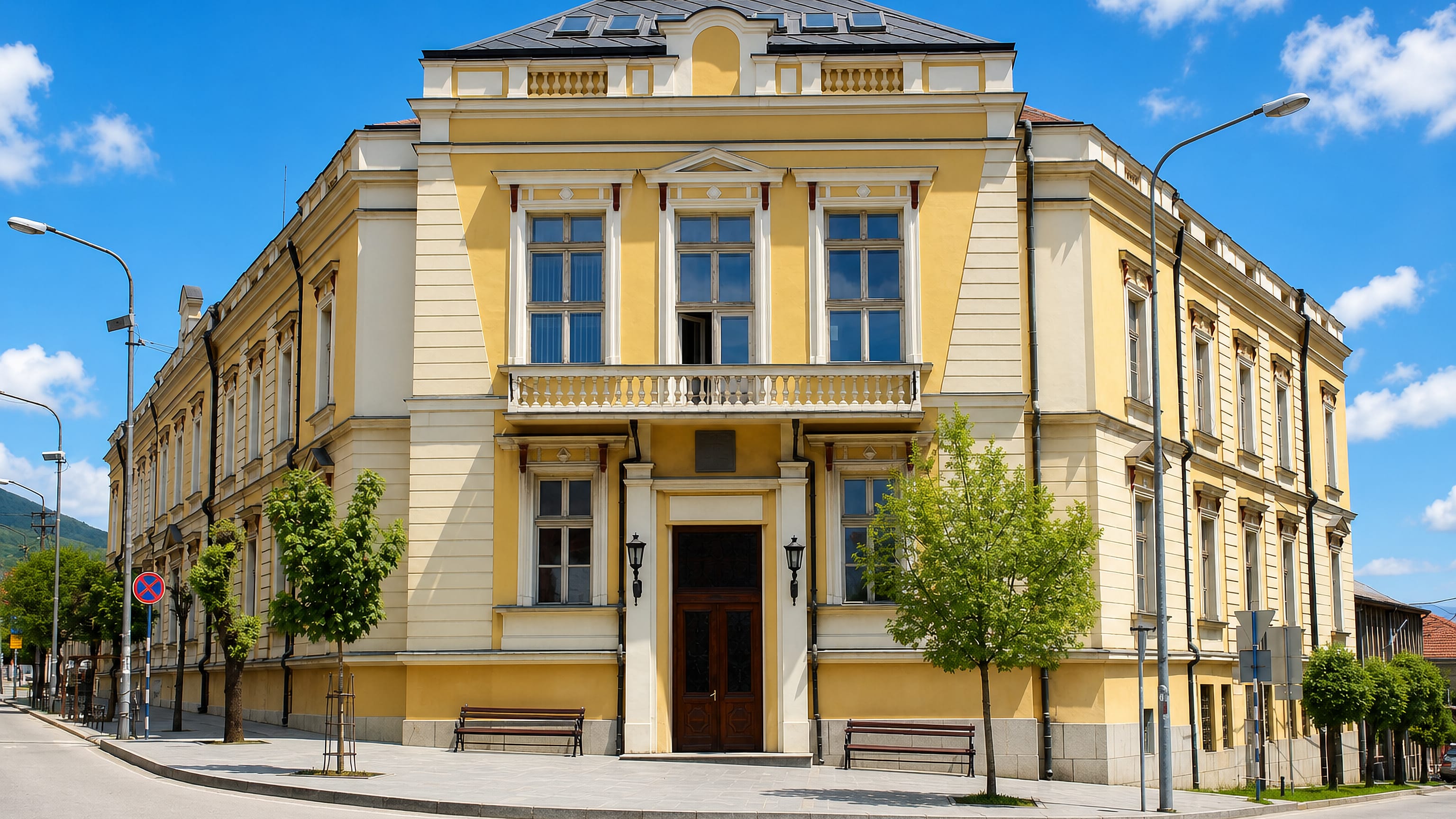A restored yellow neoclassical corner building on a quiet street in Vranje, southern Serbia.