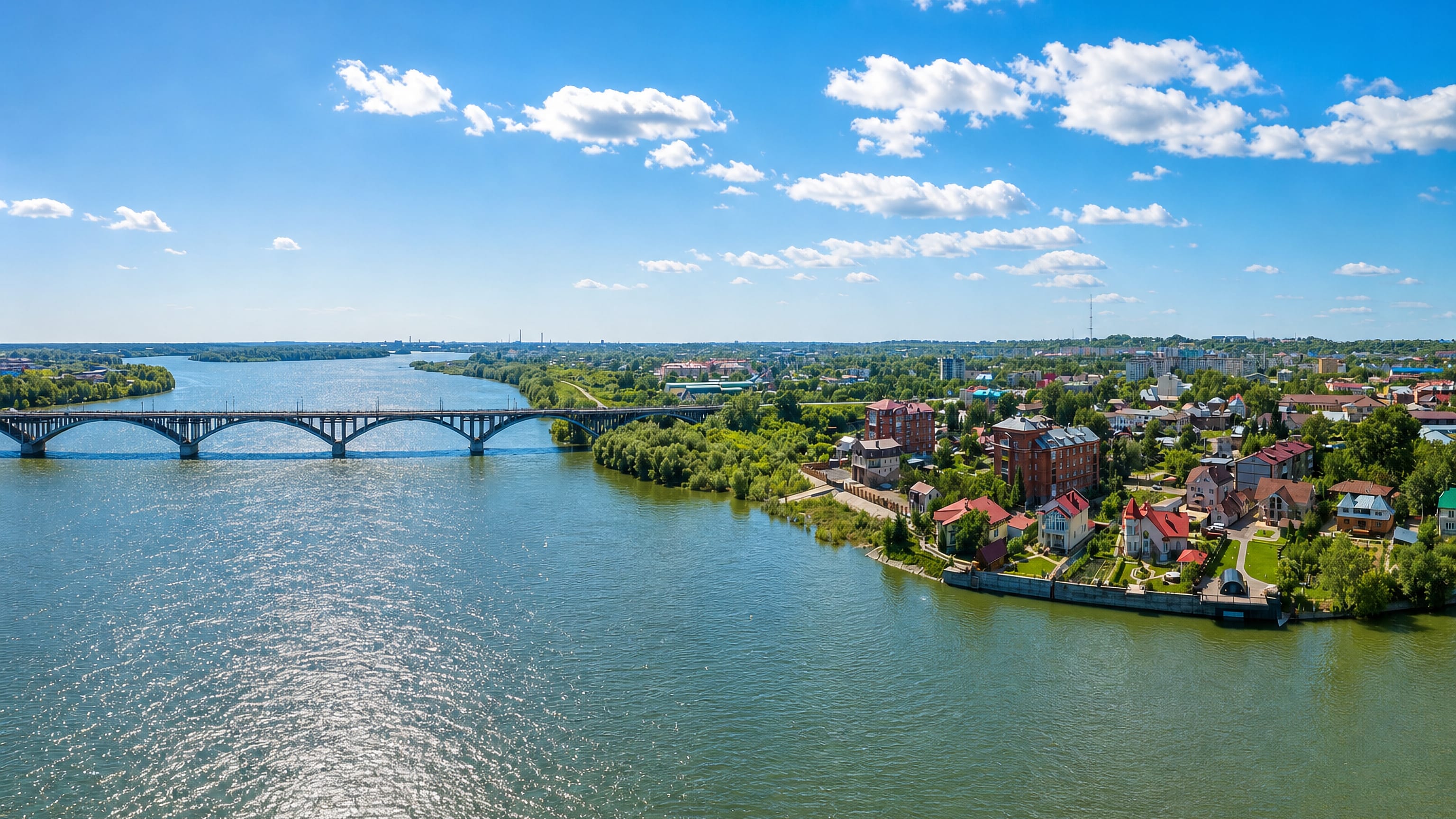 Aerial view of the Biya River, its long arched bridge and riverside houses on the edge of Biysk, Siberia