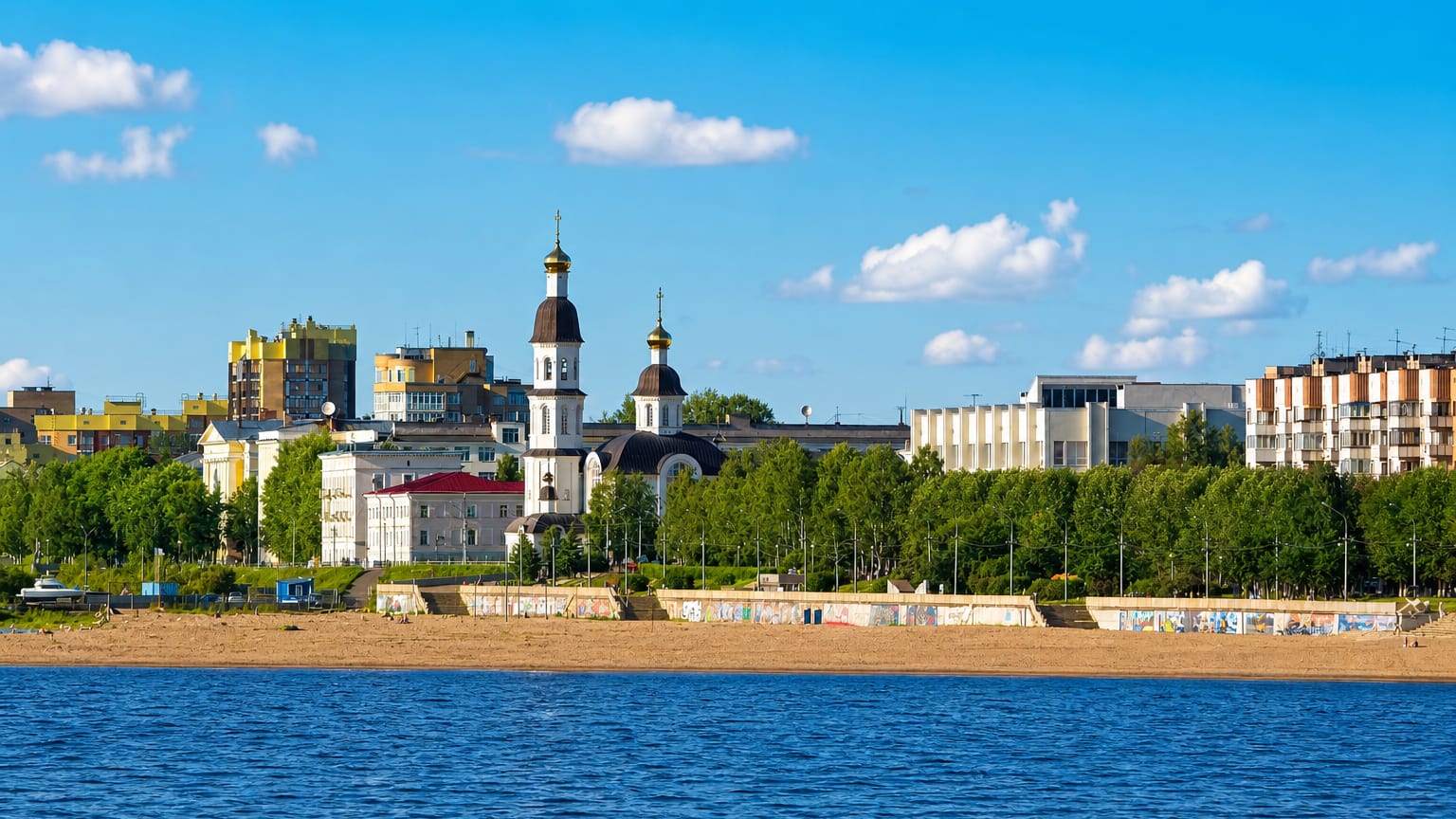 Arkhangelsk waterfront across the Northern Dvina with a white church, embankment and Soviet-era buildings.