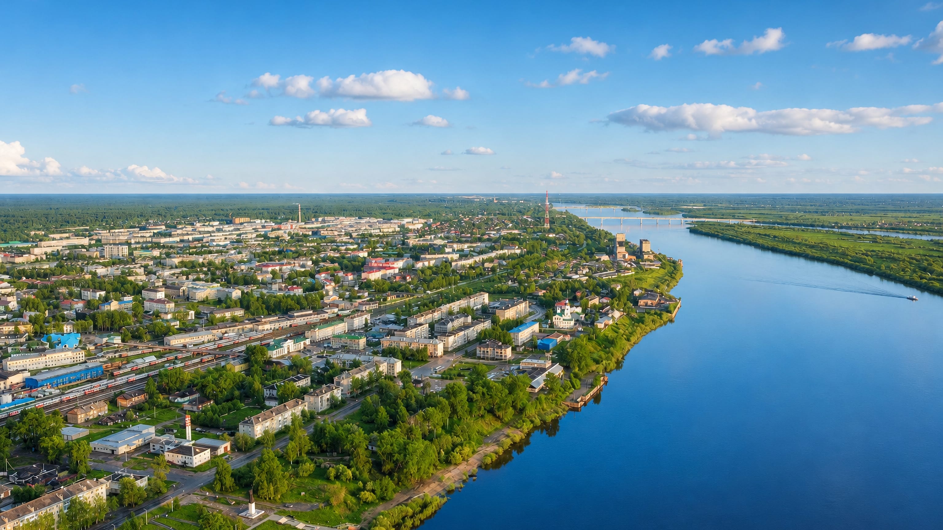 Aerial view of Kotlas stretching along the wide Northern Dvina River amid rail yards and green forest.