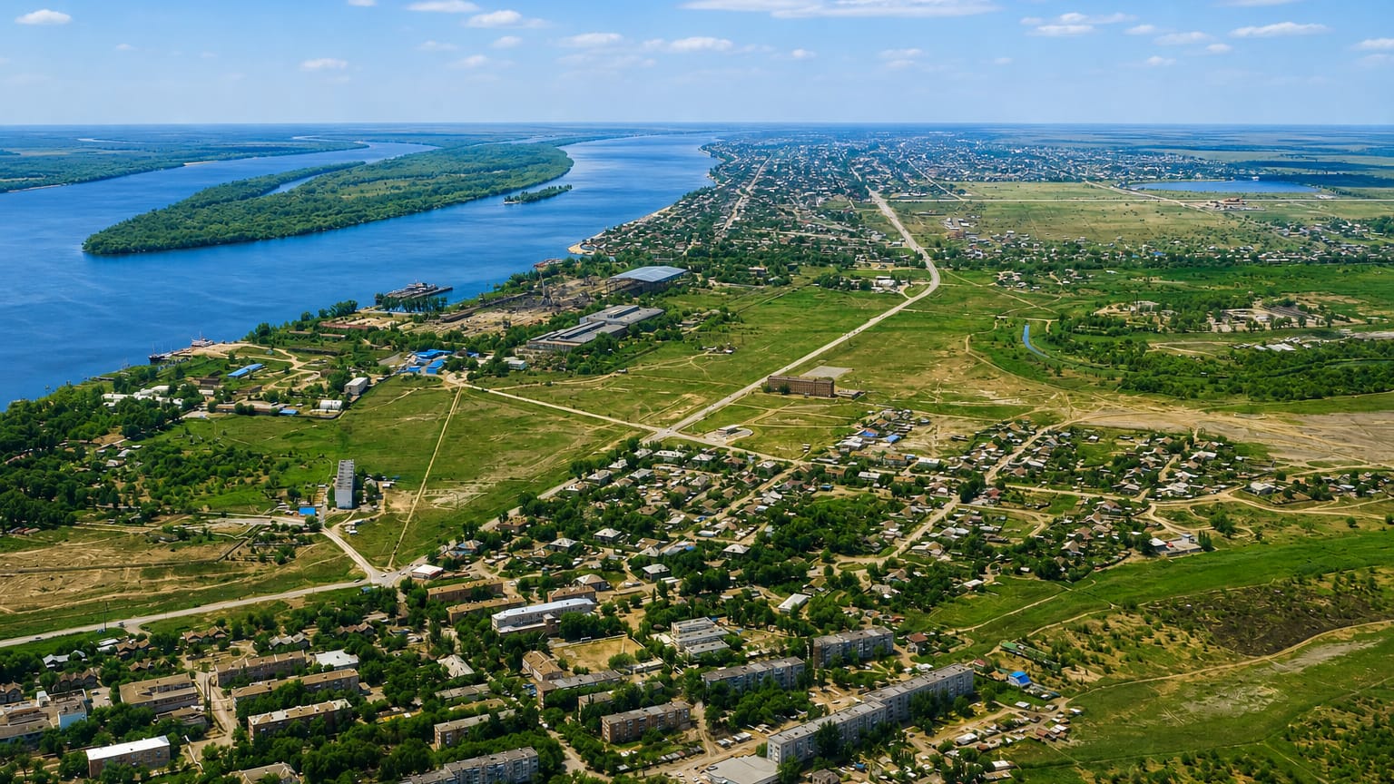 Aerial of Astrakhan's low-rise sprawl along the wide Volga river and its green delta islands.