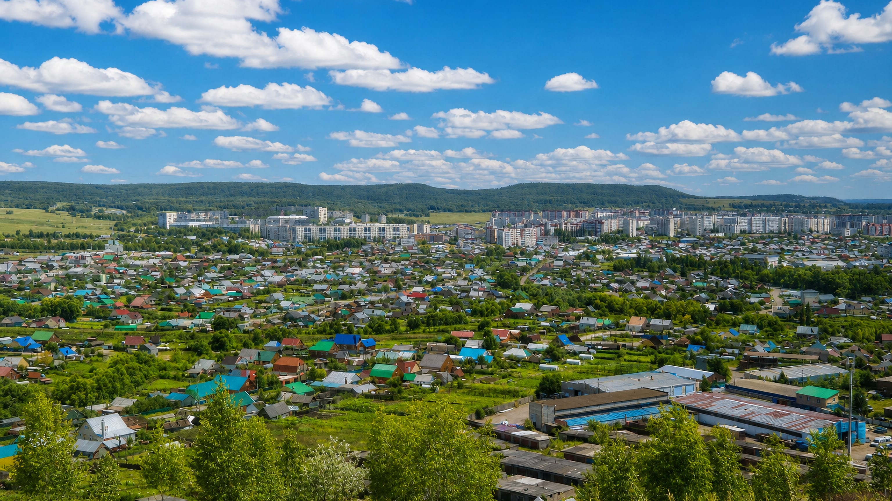 Oktyabrsky, Russia, from a hillside: coloured house roofs, apartment blocks and wooded Bashkir hills.