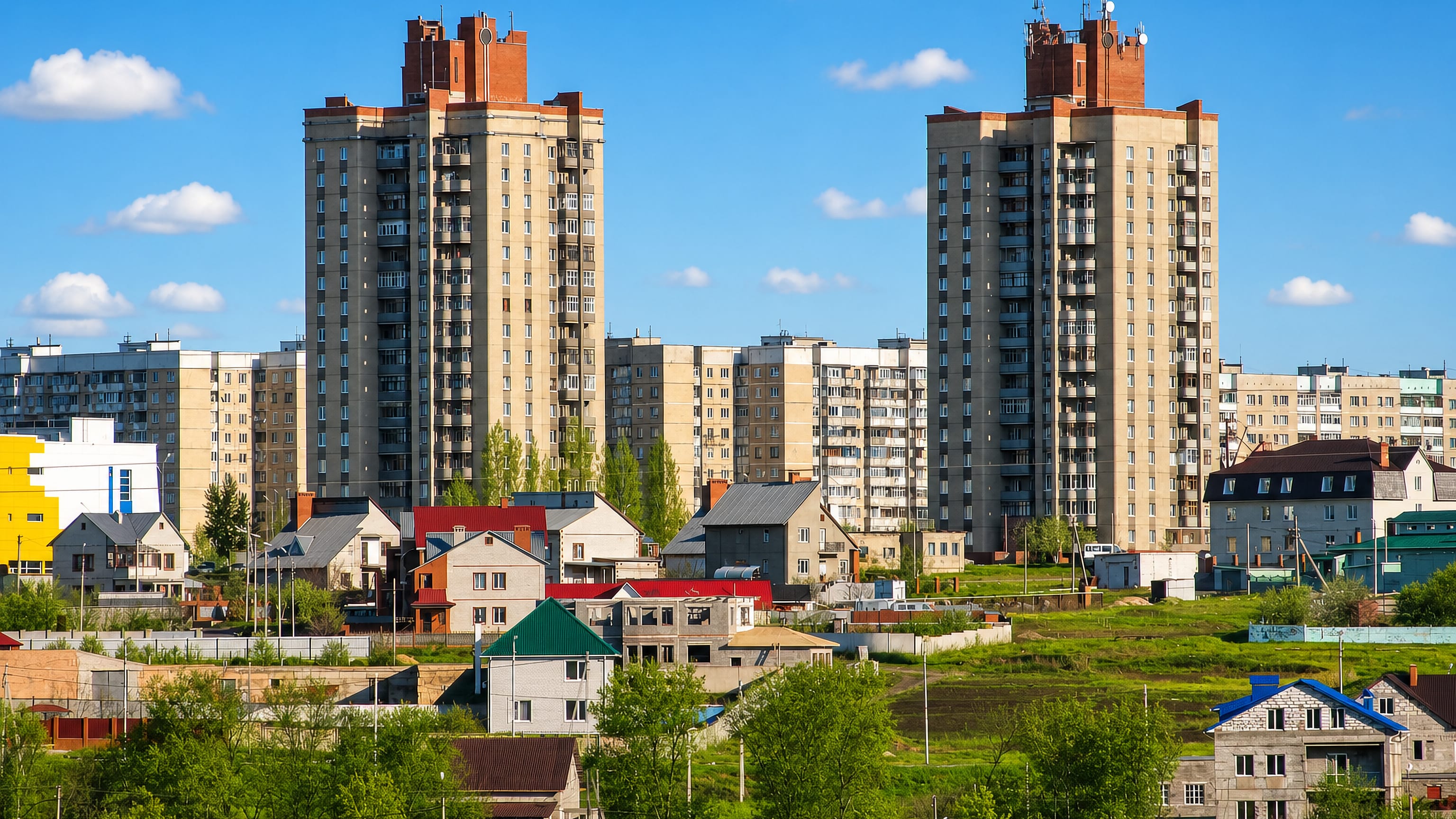 Soviet-era apartment towers above private houses and green slopes in Gubkin, Belgorod Oblast
