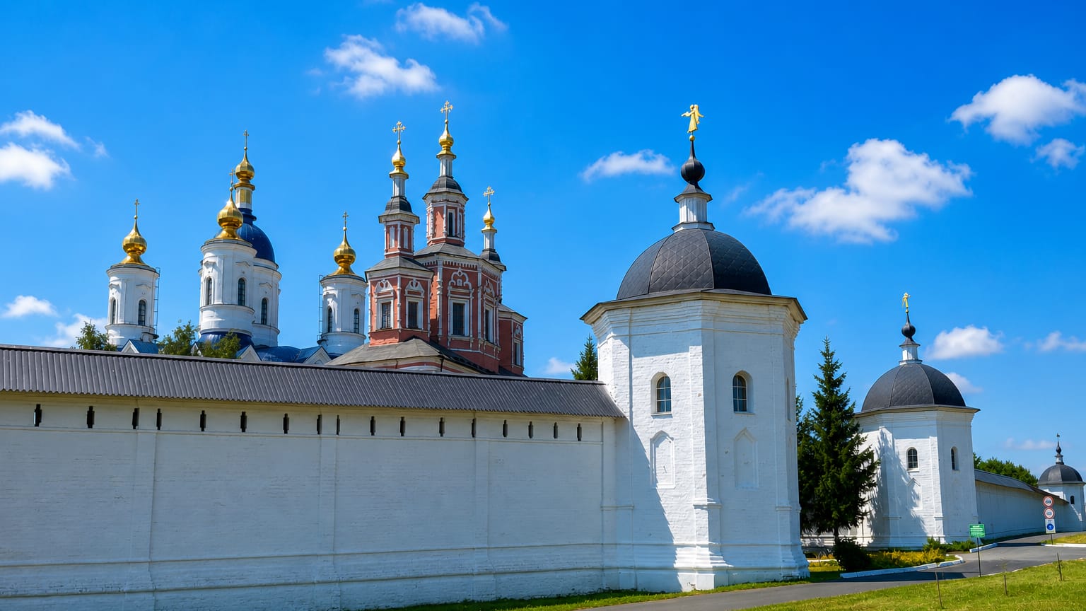 Whitewashed walls and golden-domed churches of Svensky Monastery under a blue summer sky in Bryansk, Russia.
