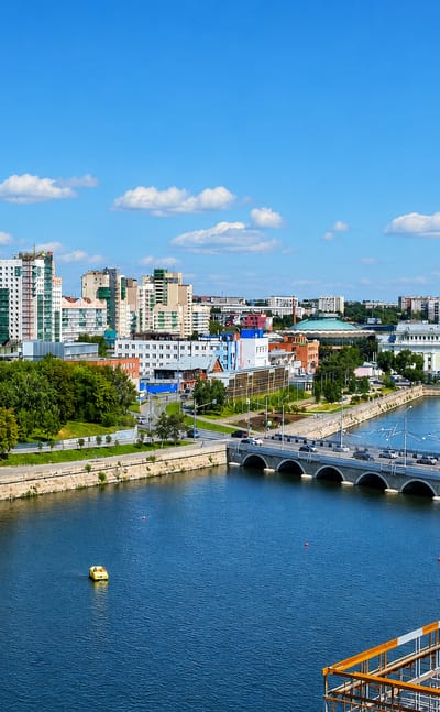 Riverfront city view with an arched bridge, fountains and skyline across the water in Chelyabinsk, Russia