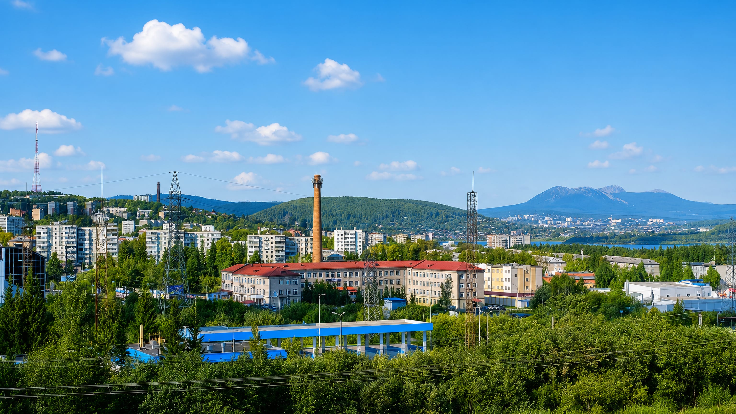 Zlatoust in the Ural Mountains, with wooded ridges, a factory chimney, apartment blocks and the city pond.