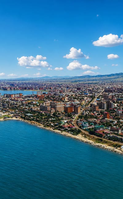 Aerial view of Makhachkala stretching along the Caspian Sea coast with hills behind.