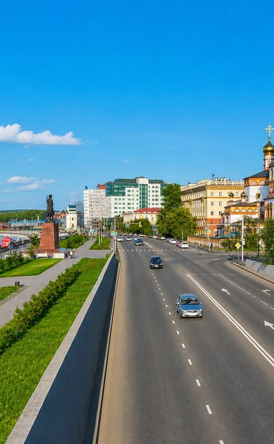Irkutsk's Angara River embankment with the ornate Church of the Epiphany and city buildings under a clear blue sky