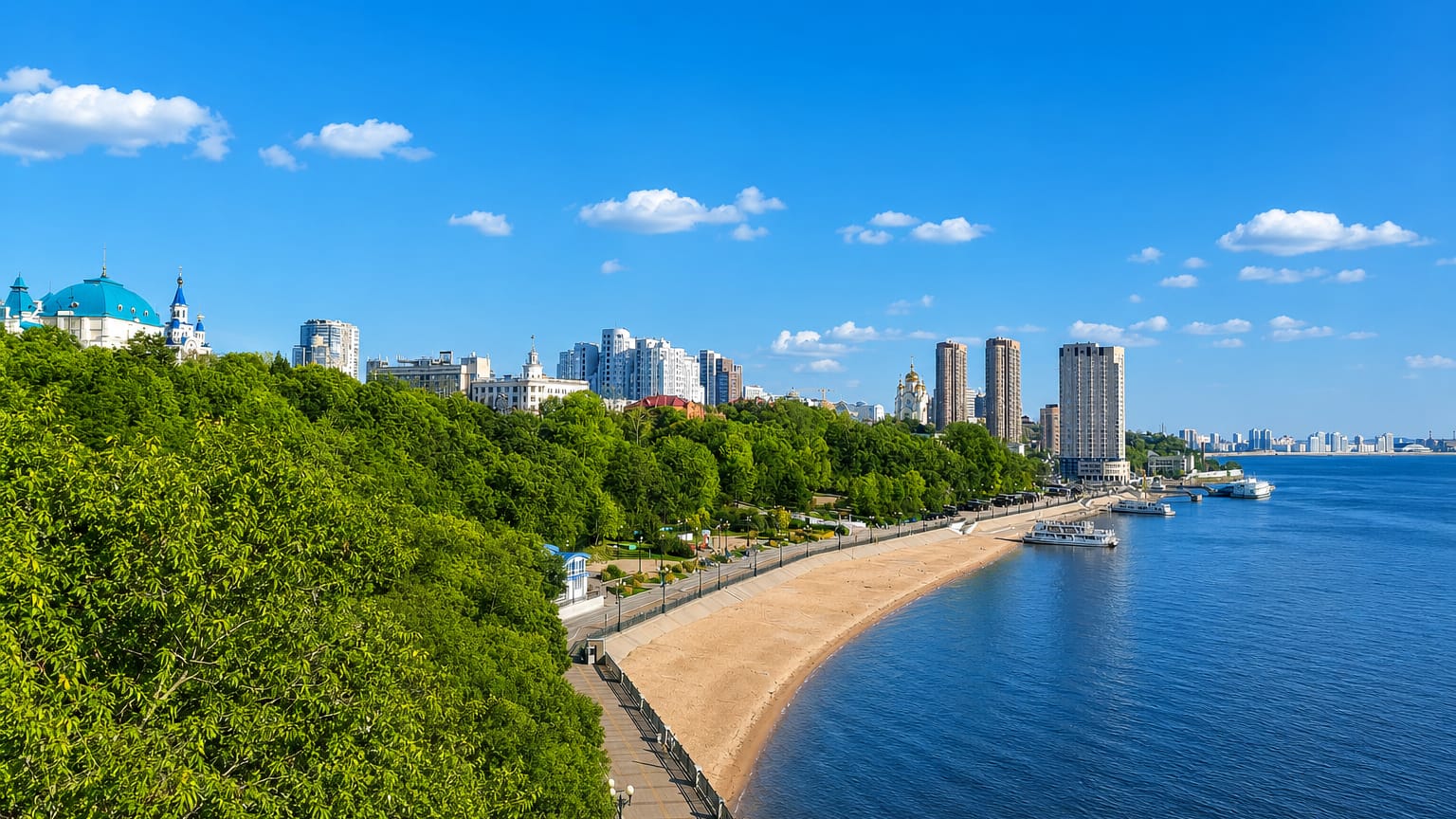 Khabarovsk's Amur River embankment with a sandy city beach, blue-domed cathedral and riverside towers.