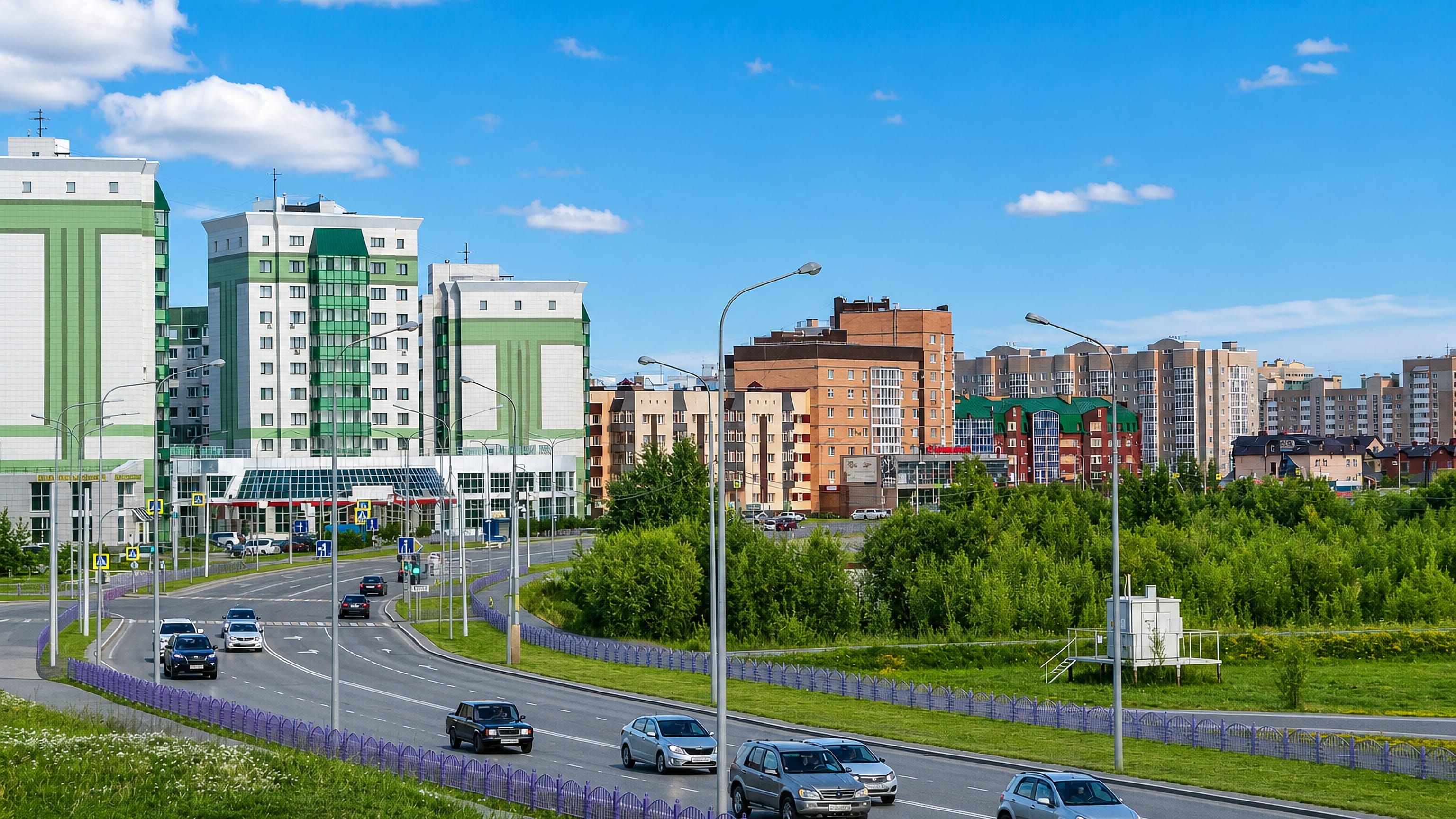 Wide boulevard in Nefteyugansk, Russia, lined with green-and-white apartment blocks under a summer sky.